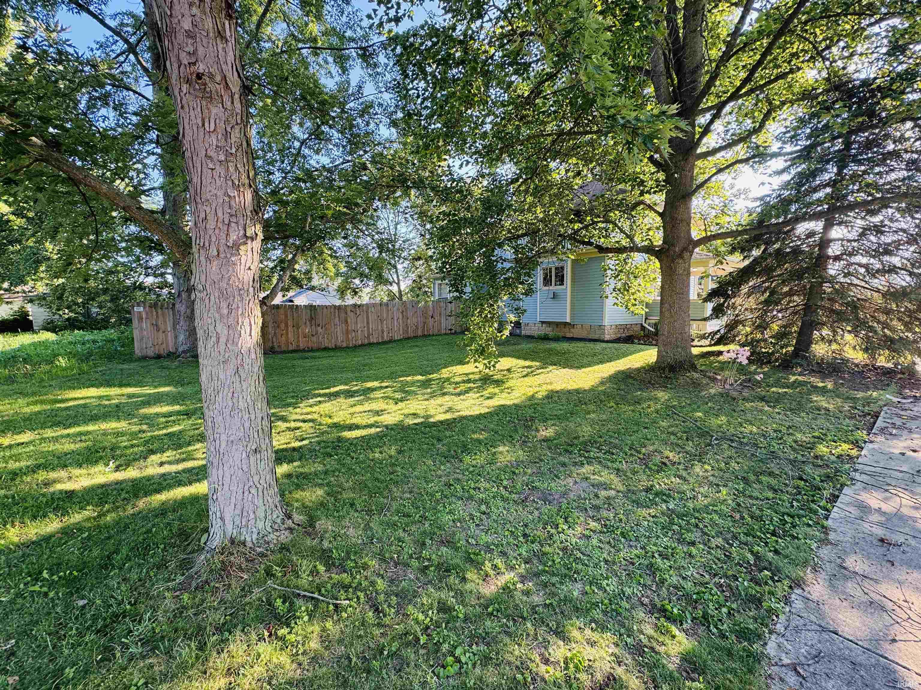 Expansive green lawn featuring mature trees providing ample shade