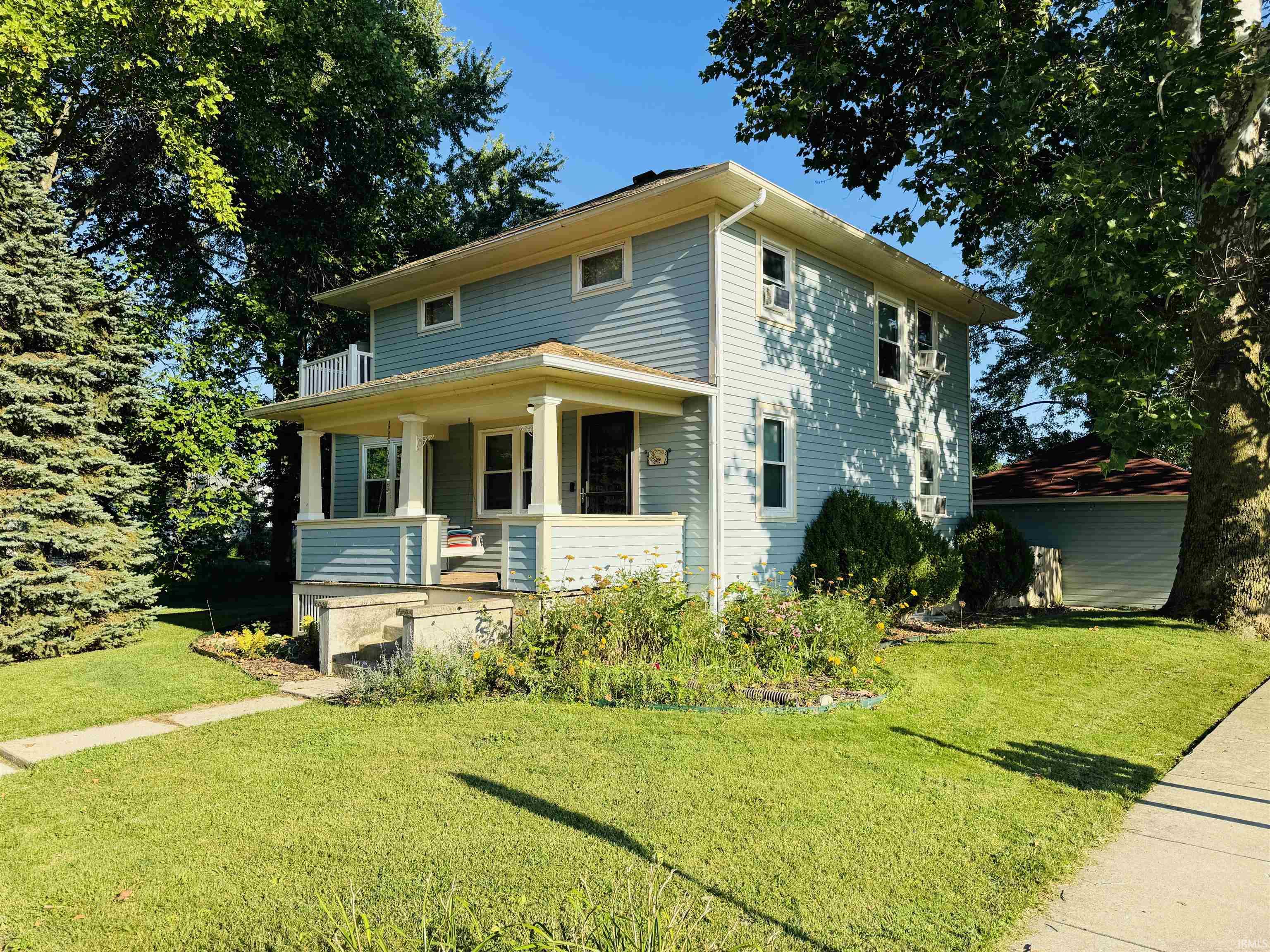 Two-story residence featuring light blue siding and a covered front porch with white columns