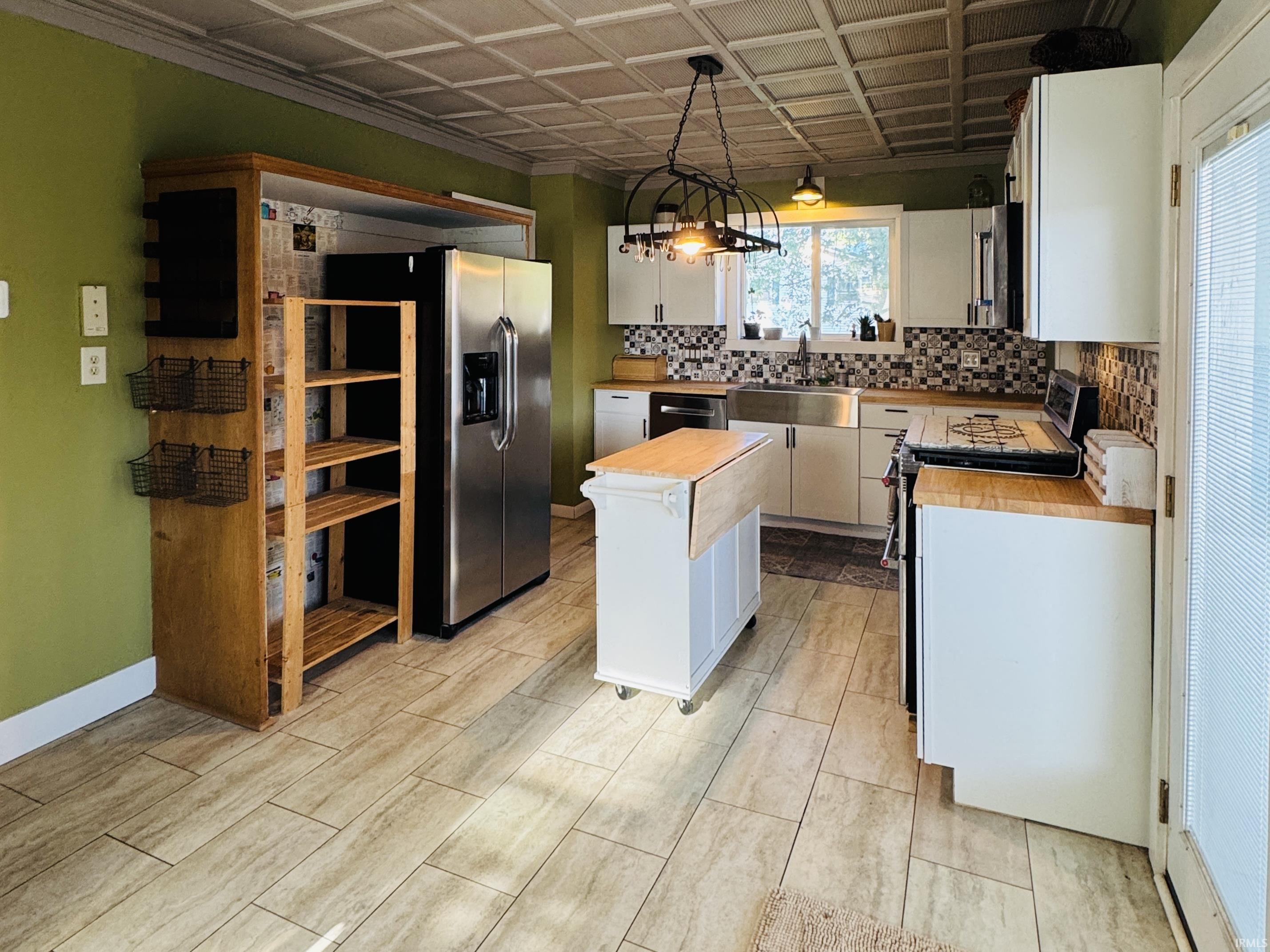 Kitchen featuring a patterned tile backsplash, wood-finish countertops, stainless steel appliances, and wood-look tile flooring