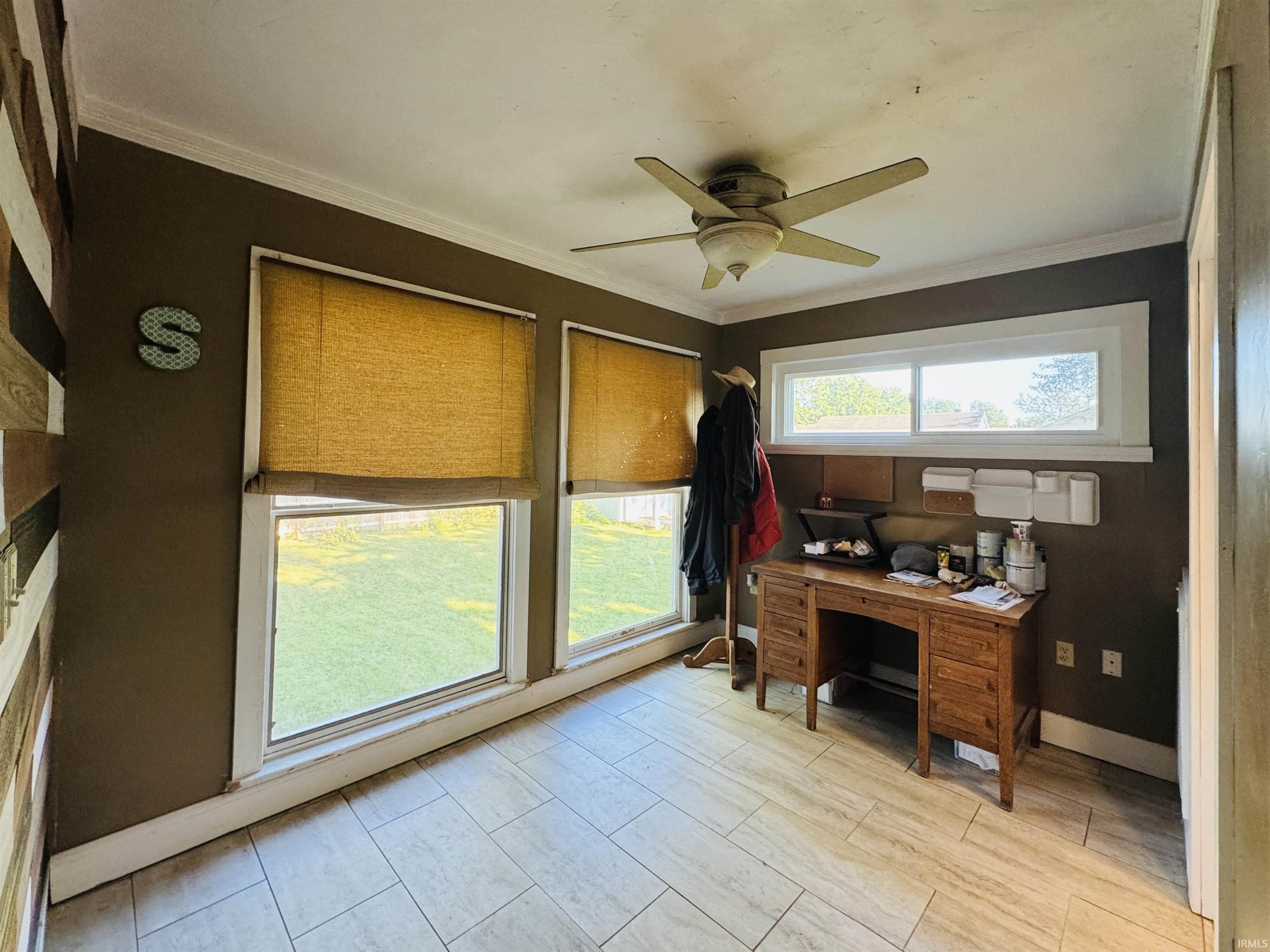 Room featuring light-toned tile flooring, three windows with white trim, and a ceiling fan