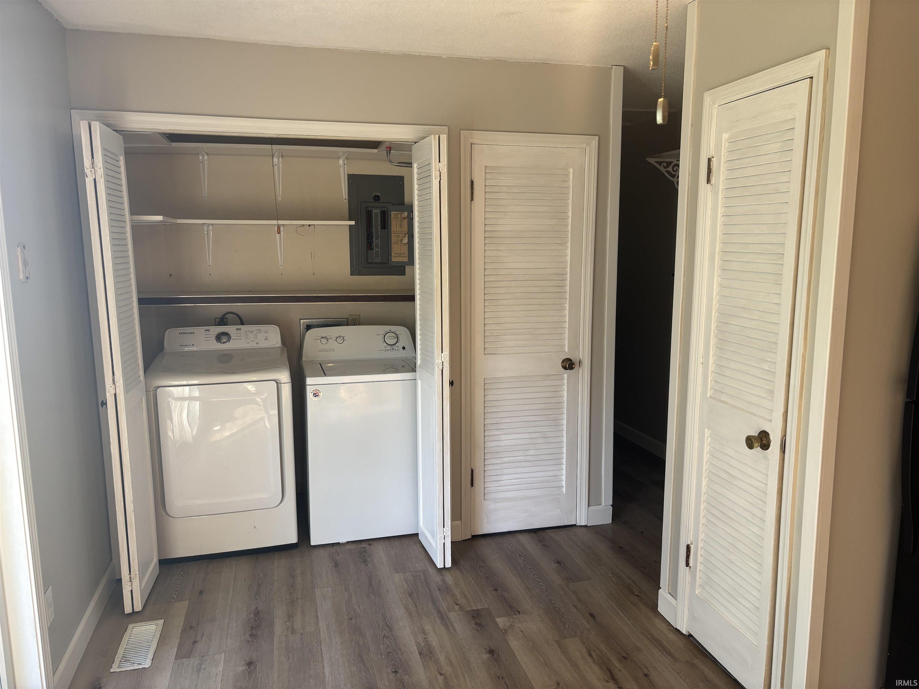 Dedicated laundry closet with bi-fold louvered doors, white washer and dryer, and overhead shelving