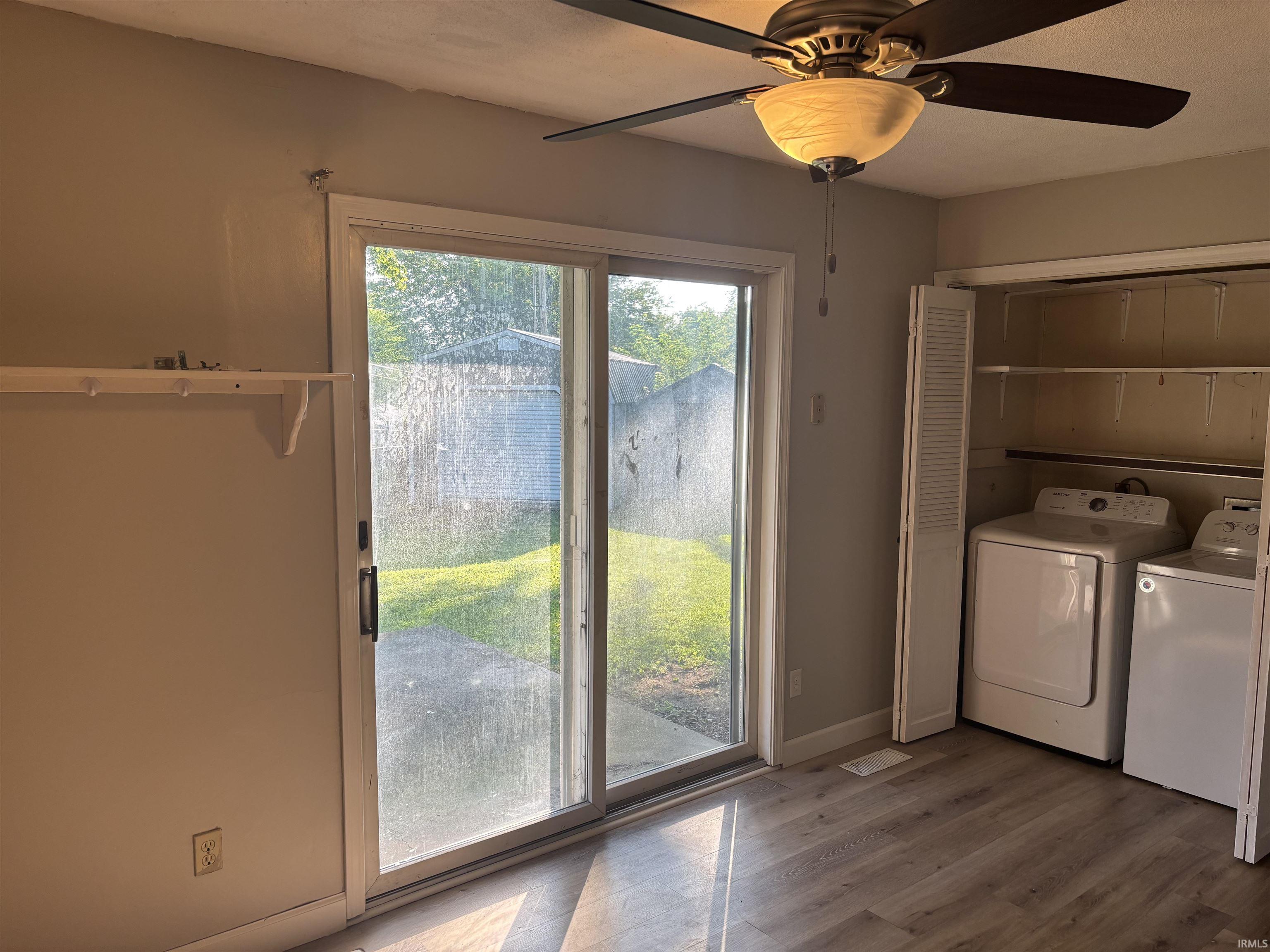 Room featuring wood-finish flooring, a ceiling fan with integrated lighting, and a sliding glass door providing access to an outdoor patio