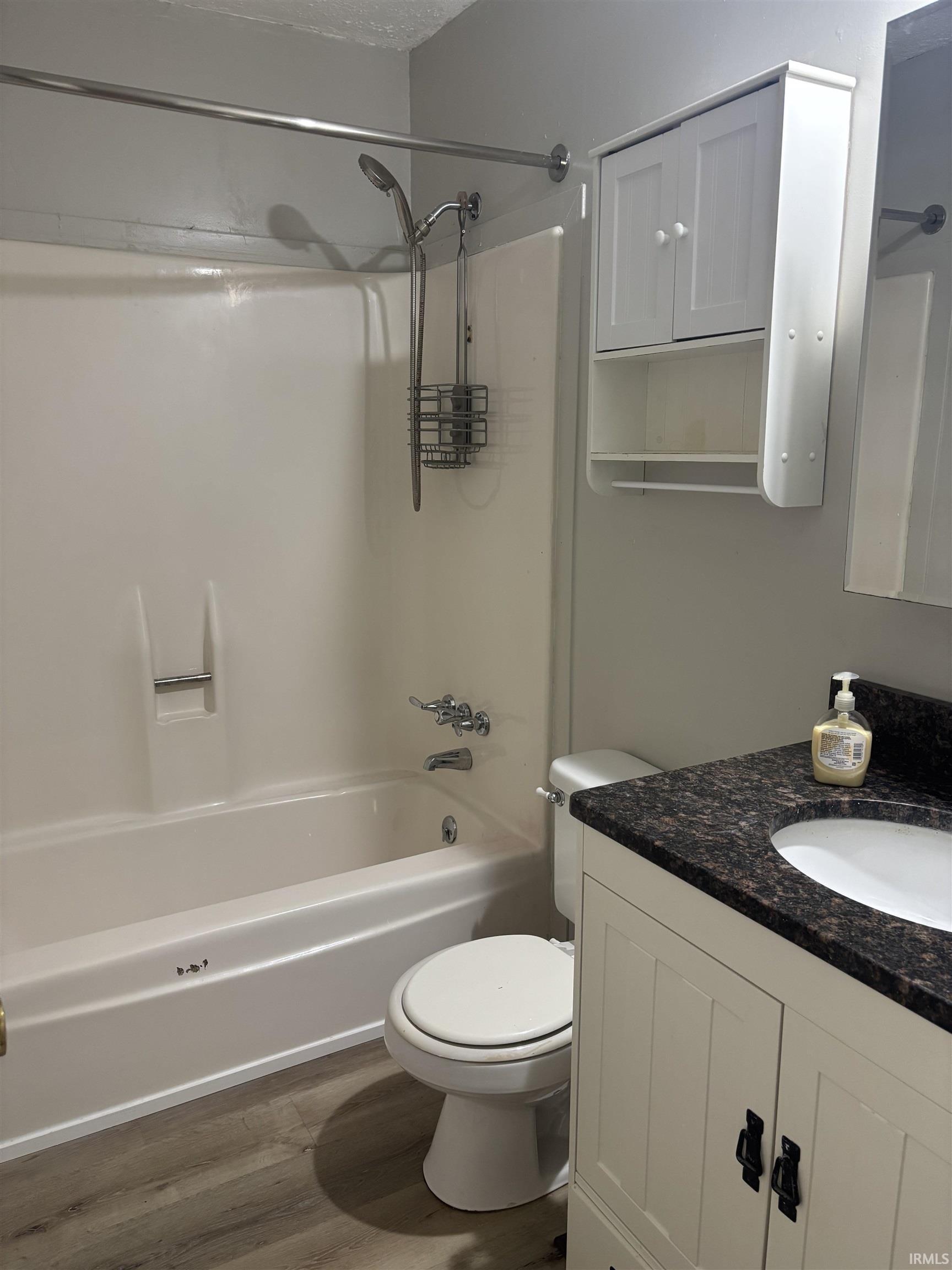Bathroom featuring a white vanity with dark countertop, undermount sink, and wood-finish flooring