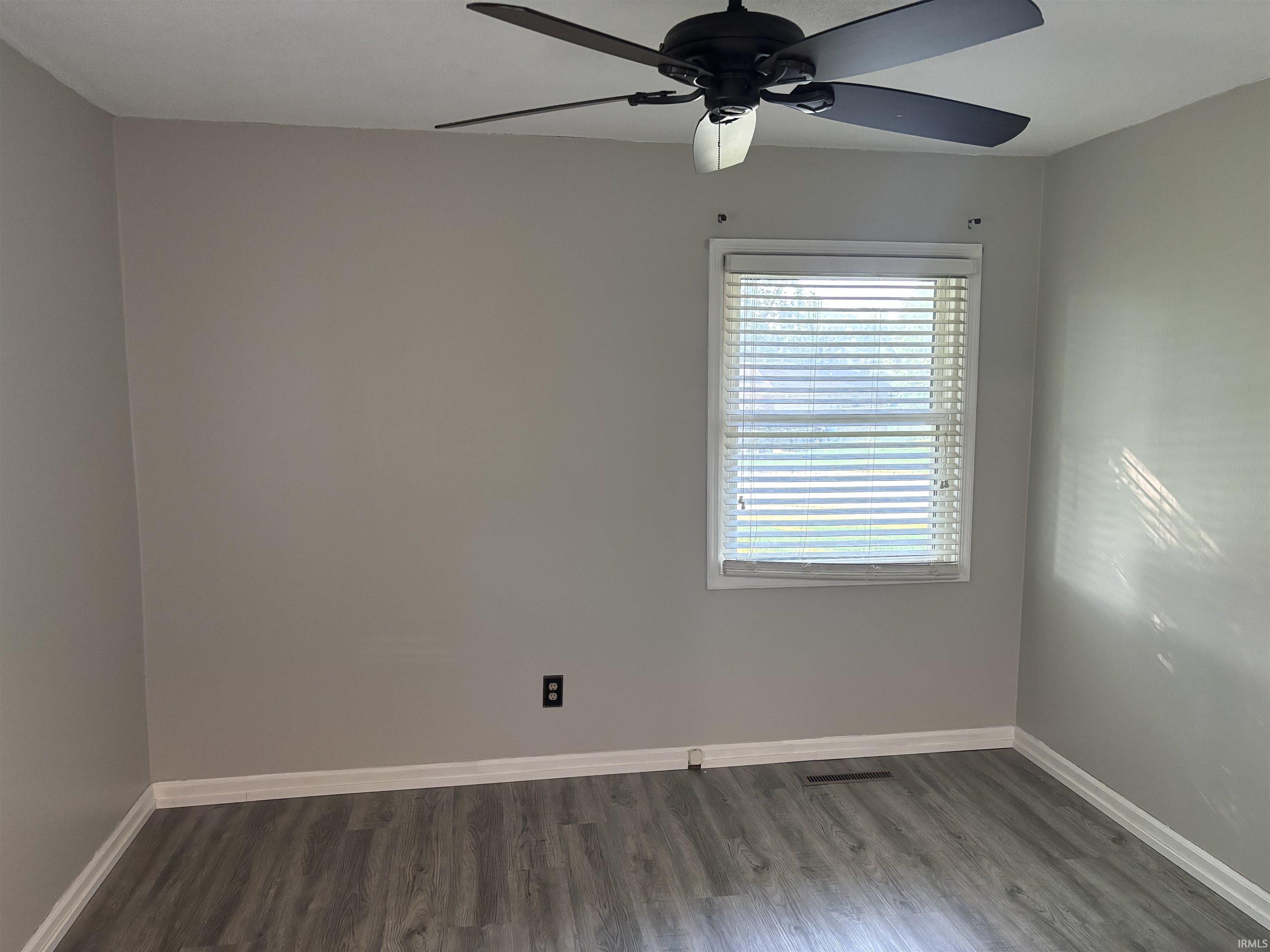 Interior room featuring grey wood-finish flooring, white baseboards, and light grey wall paint