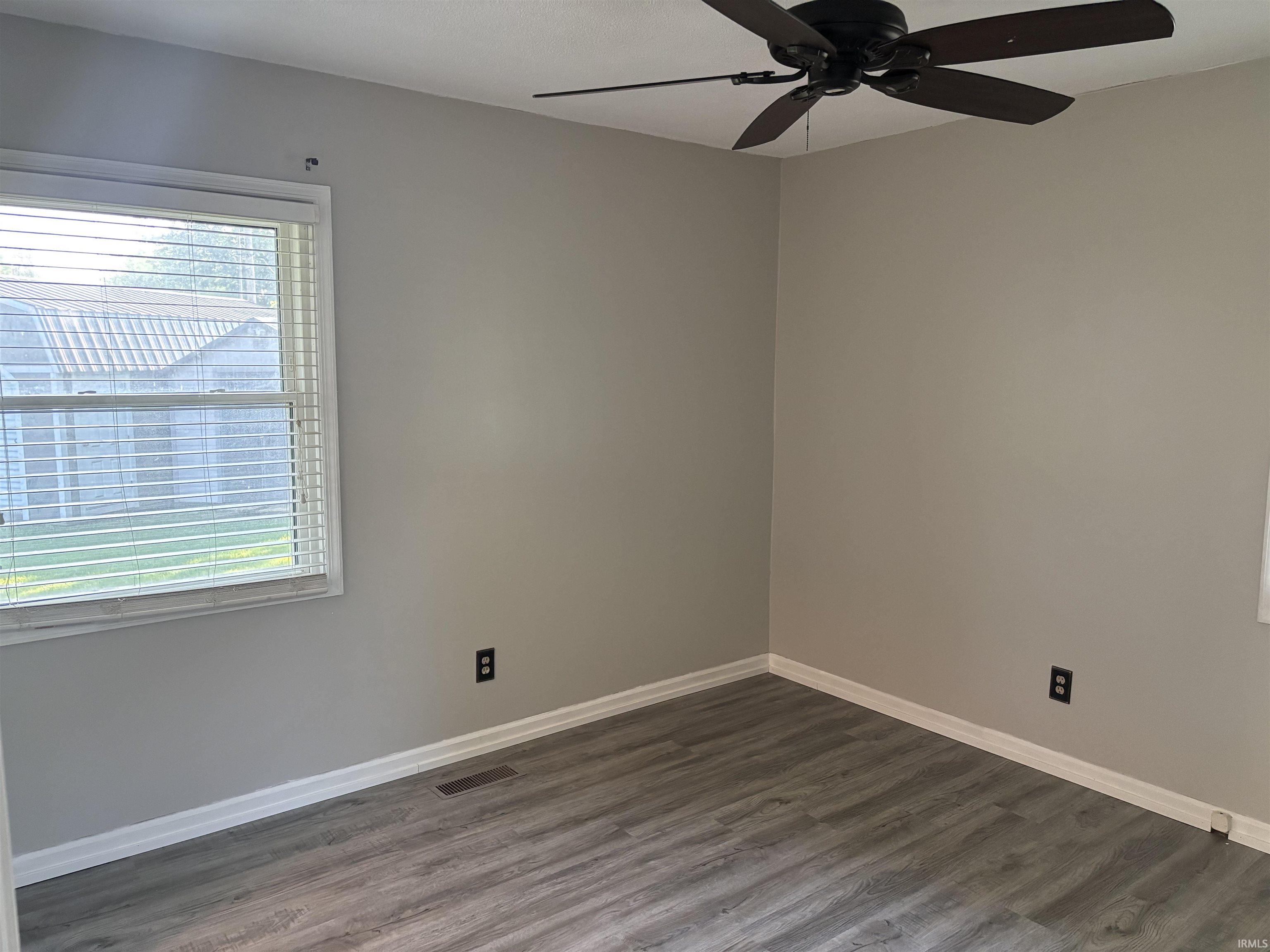 Bedroom featuring wood-finish flooring, neutral wall tones, a ceiling fan, and a window with blinds