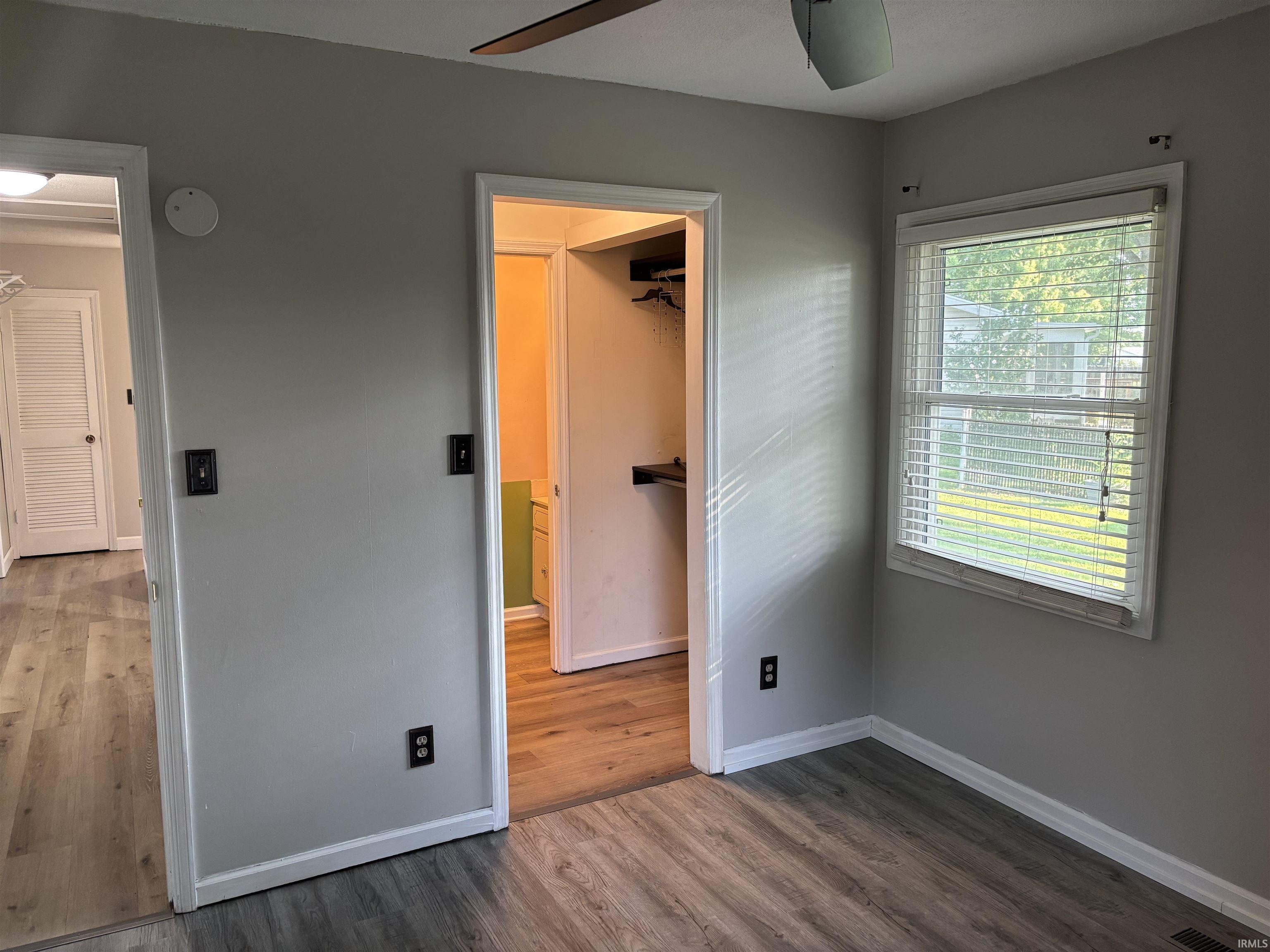 Room featuring wood-finish flooring, light gray wall paint, and a window with blinds