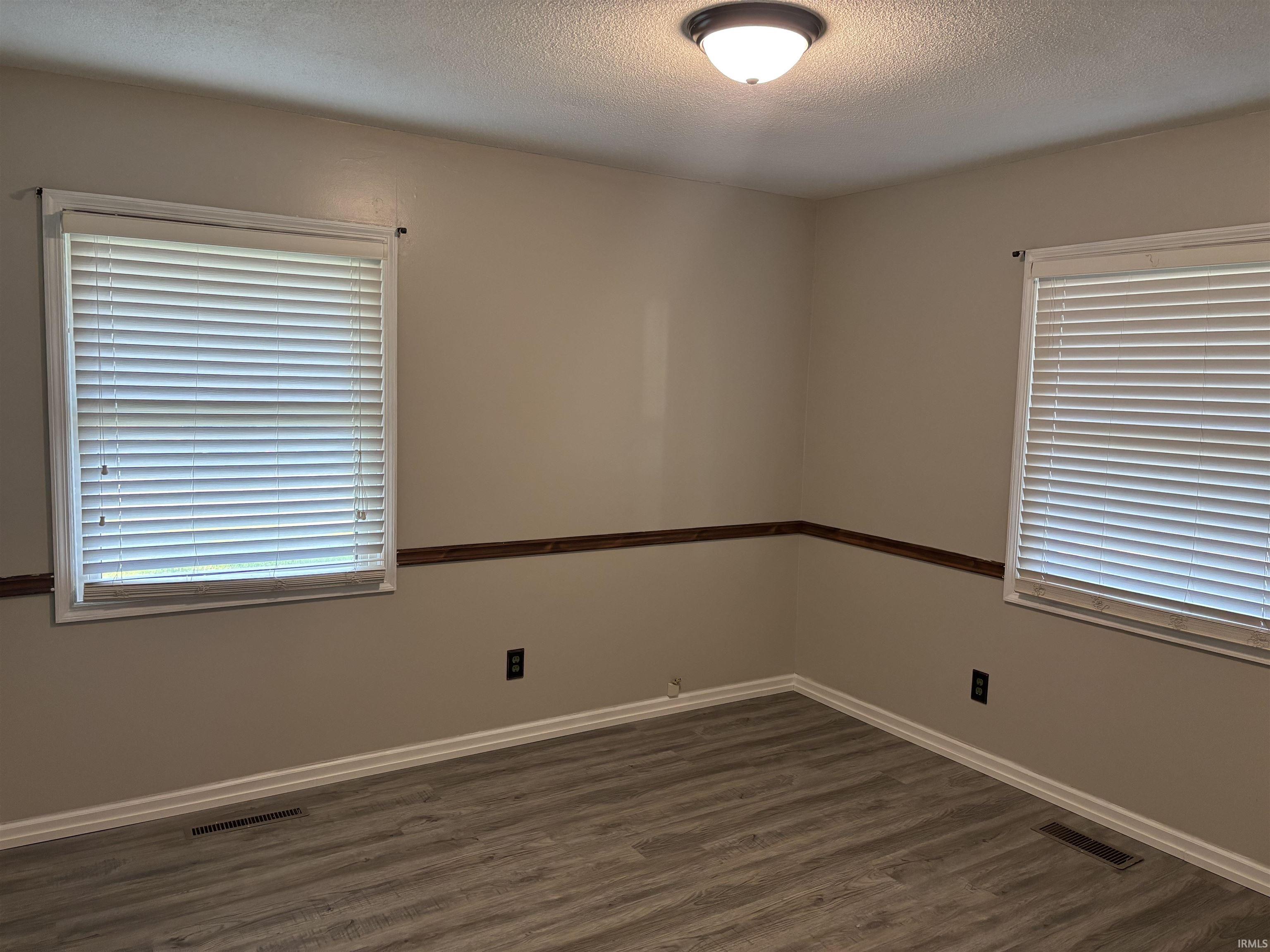 Interior room featuring wood-finish flooring, light tan walls, and white trim