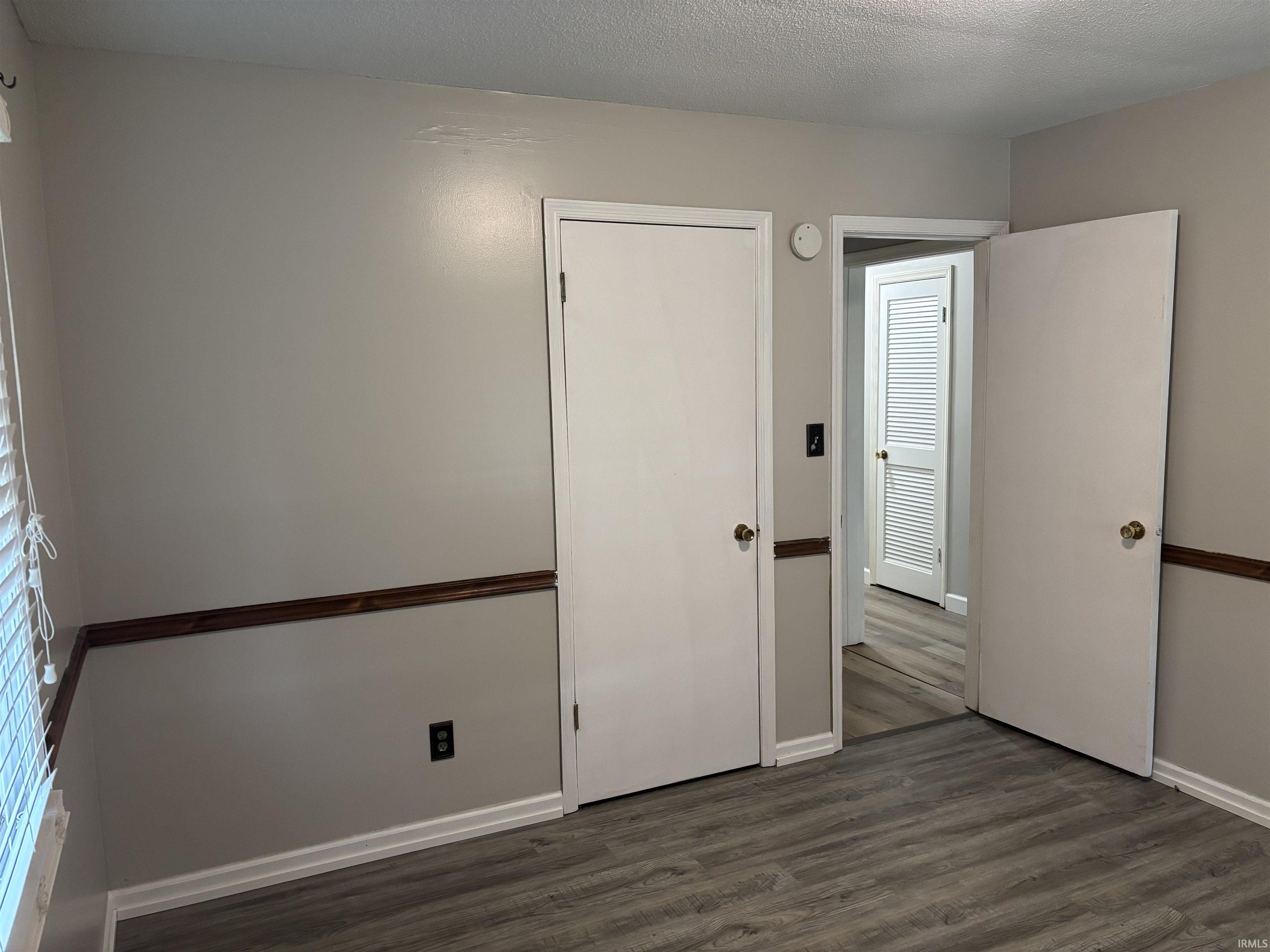 Interior room featuring wood-finish flooring, light gray wall paint, and white baseboards