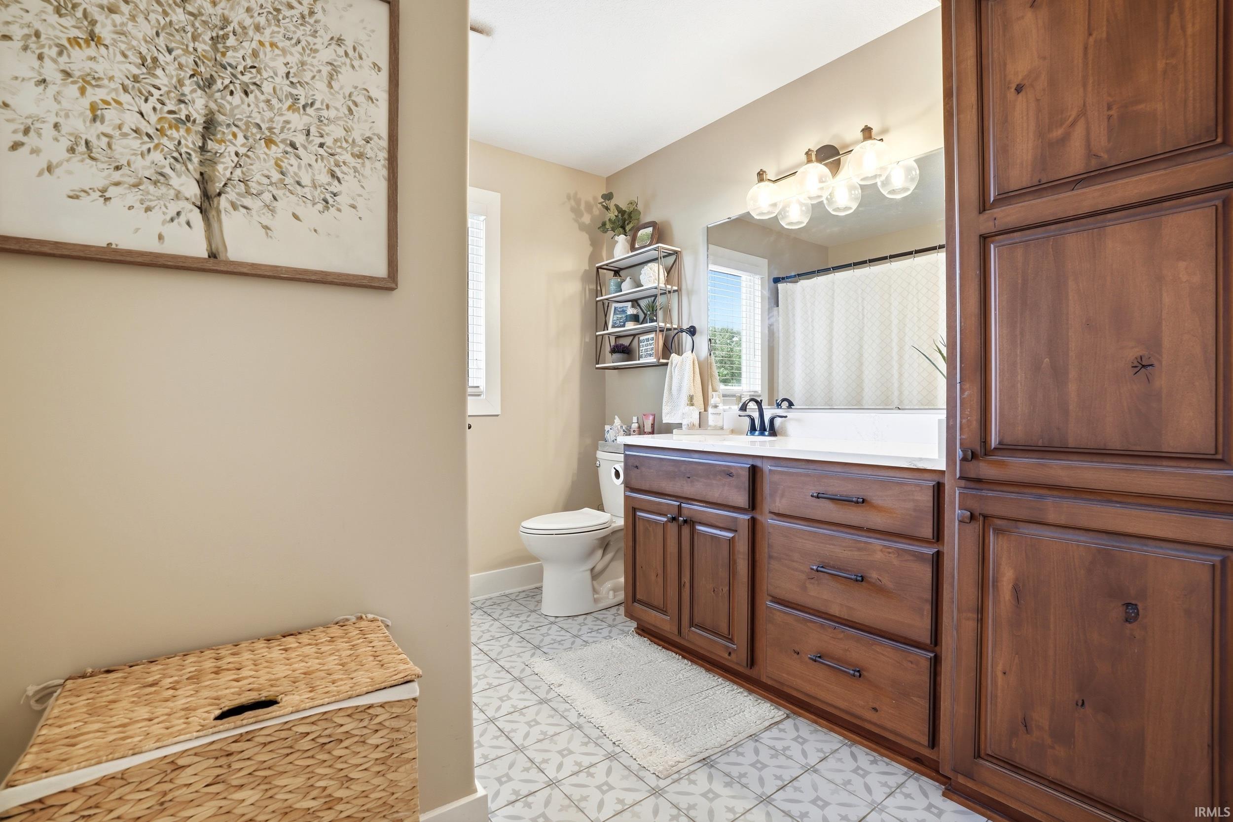 Bathroom featuring a wood-finish vanity with a single sink, light-toned countertop, and dark-finish faucet