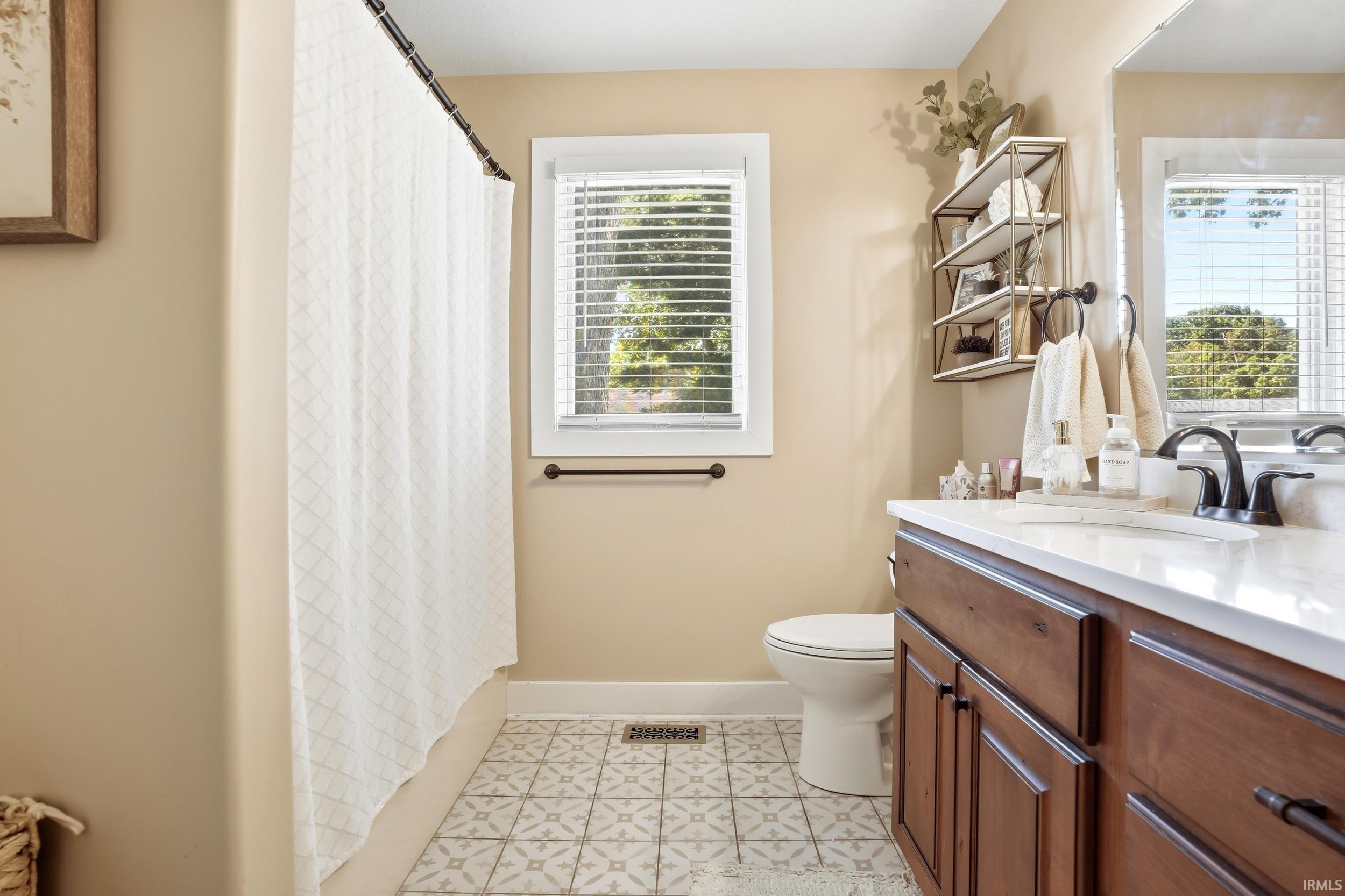 Spa-inspired primary bathroom showcasing a dual vanity with wood-finish cabinetry, white quartz countertop, and brushed nickel fixtures