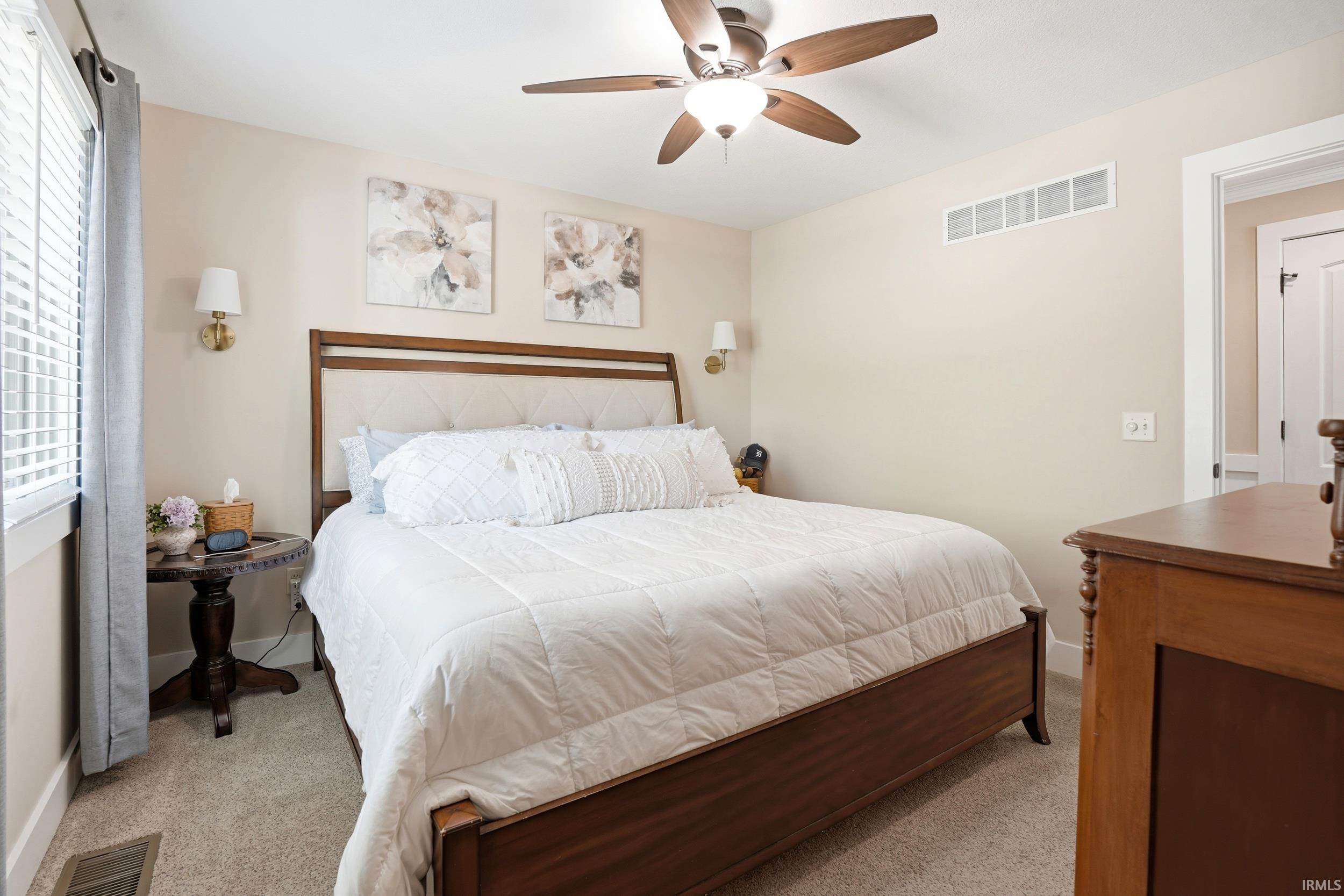Carpeted room featuring a ceiling fan with integrated lighting, a window with blinds, and a built-in wall vent