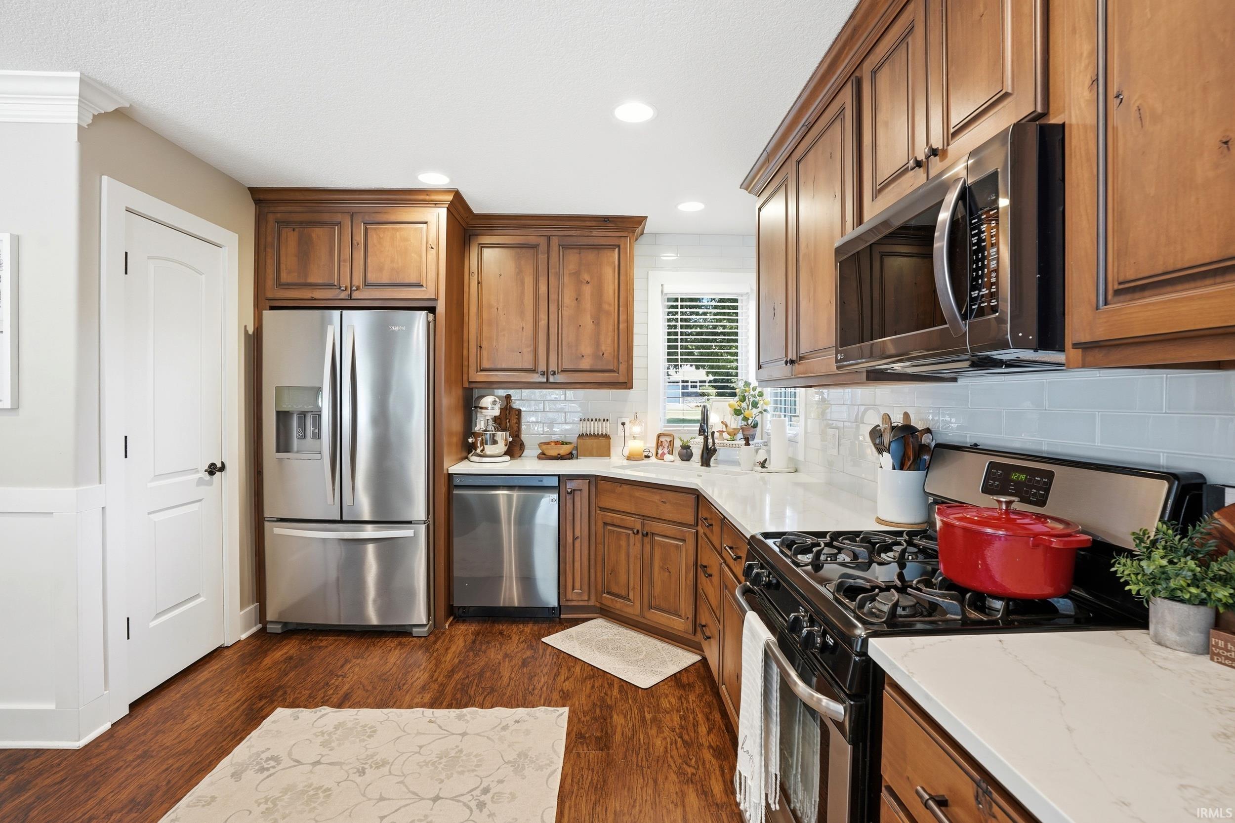 Warm wood cabinetry and stainless steel appliances define this well-appointed kitchen, featuring a gas cooktop, built-in microwave, and French-door refrigerator