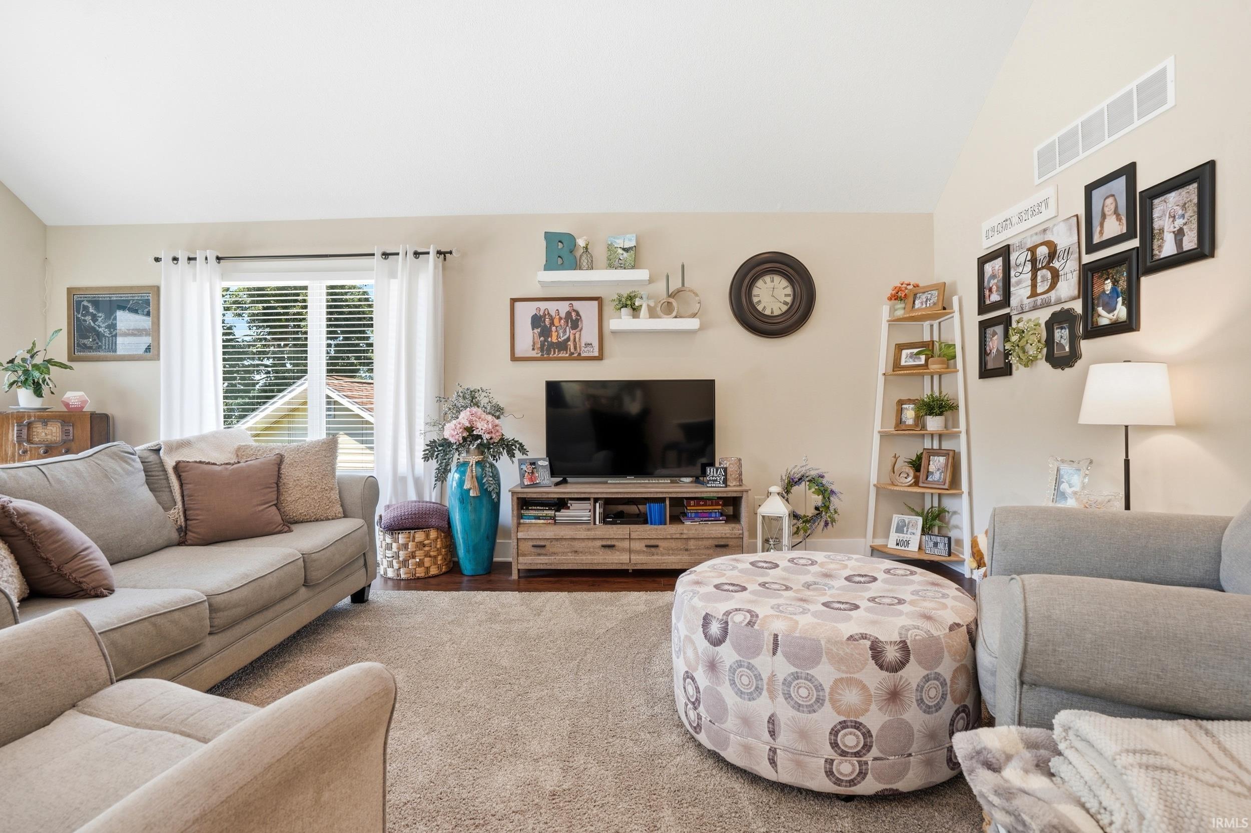 Vaulted ceiling with horizontal ventilation, light-toned walls, and wood-finish flooring