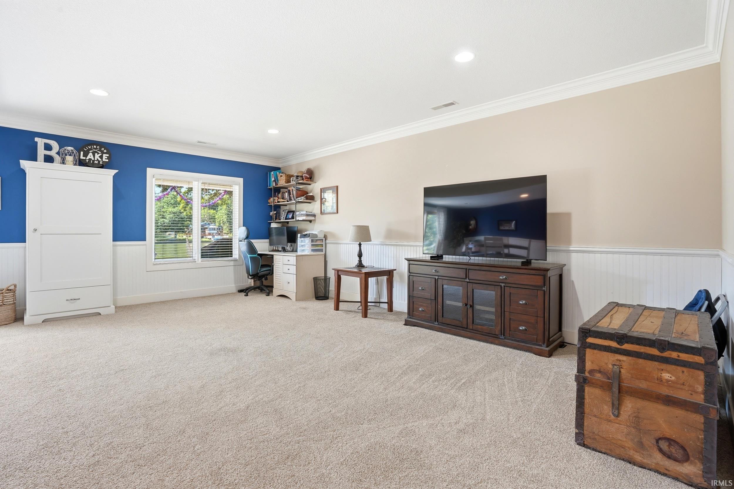 Spacious recreation room featuring soft carpet flooring, recessed ceiling lighting, and large windows with natural light