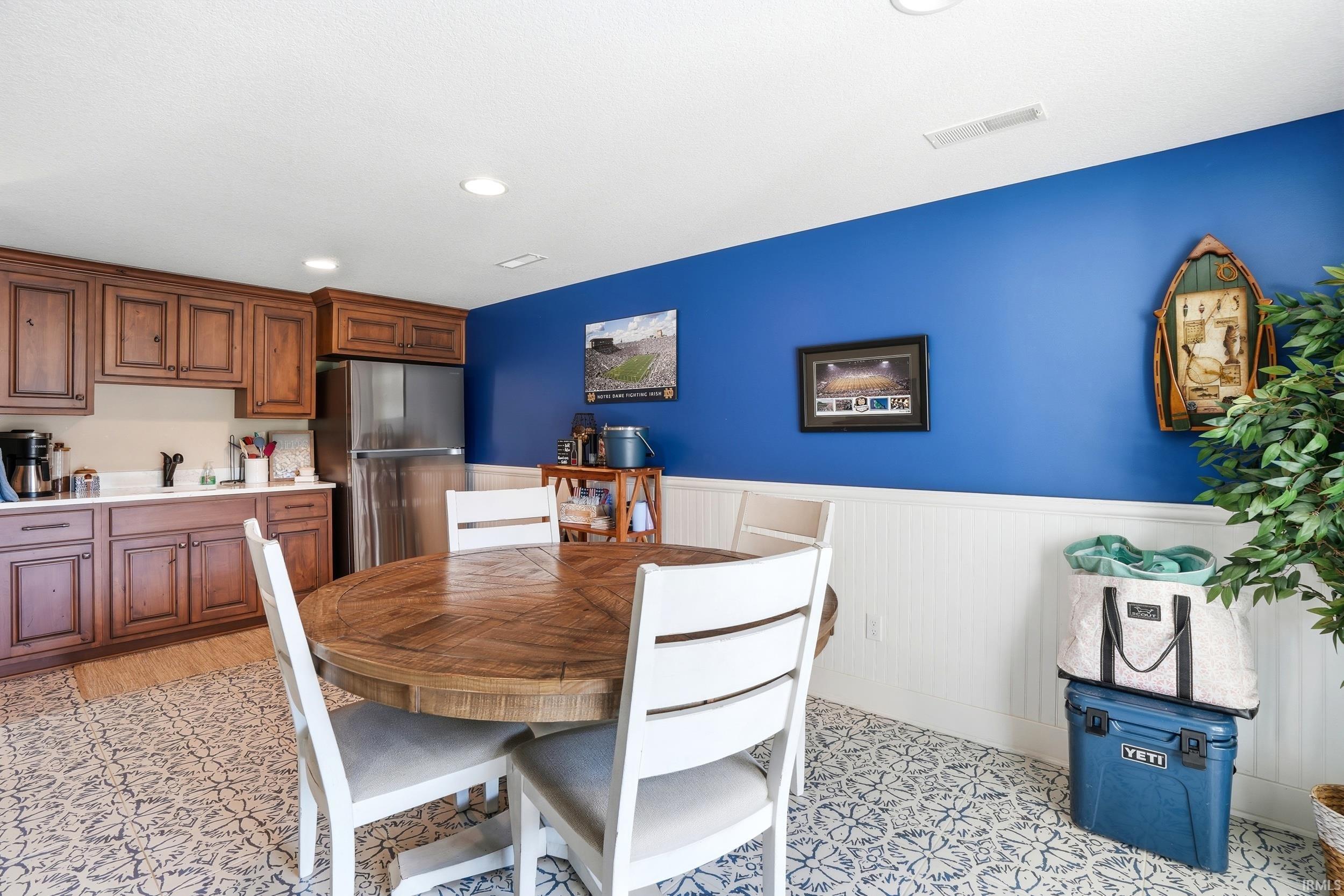 Spacious dining area with a round wood-finish table and coordinating chairs, anchored by vibrant blue accent walls and crisp white wainscoting
