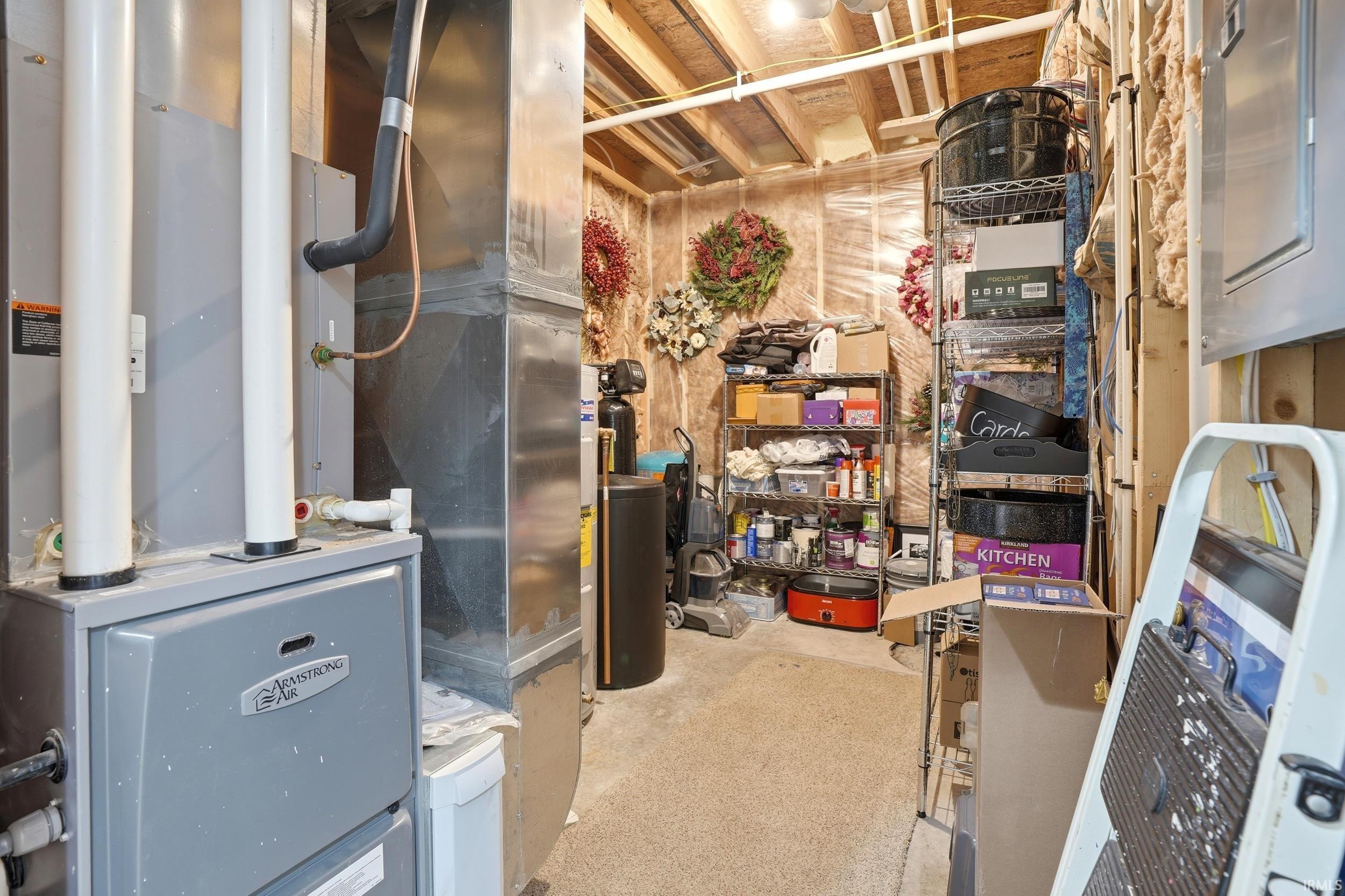 Utility room featuring a furnace with visible ductwork, a water softener system, and exposed wood framing