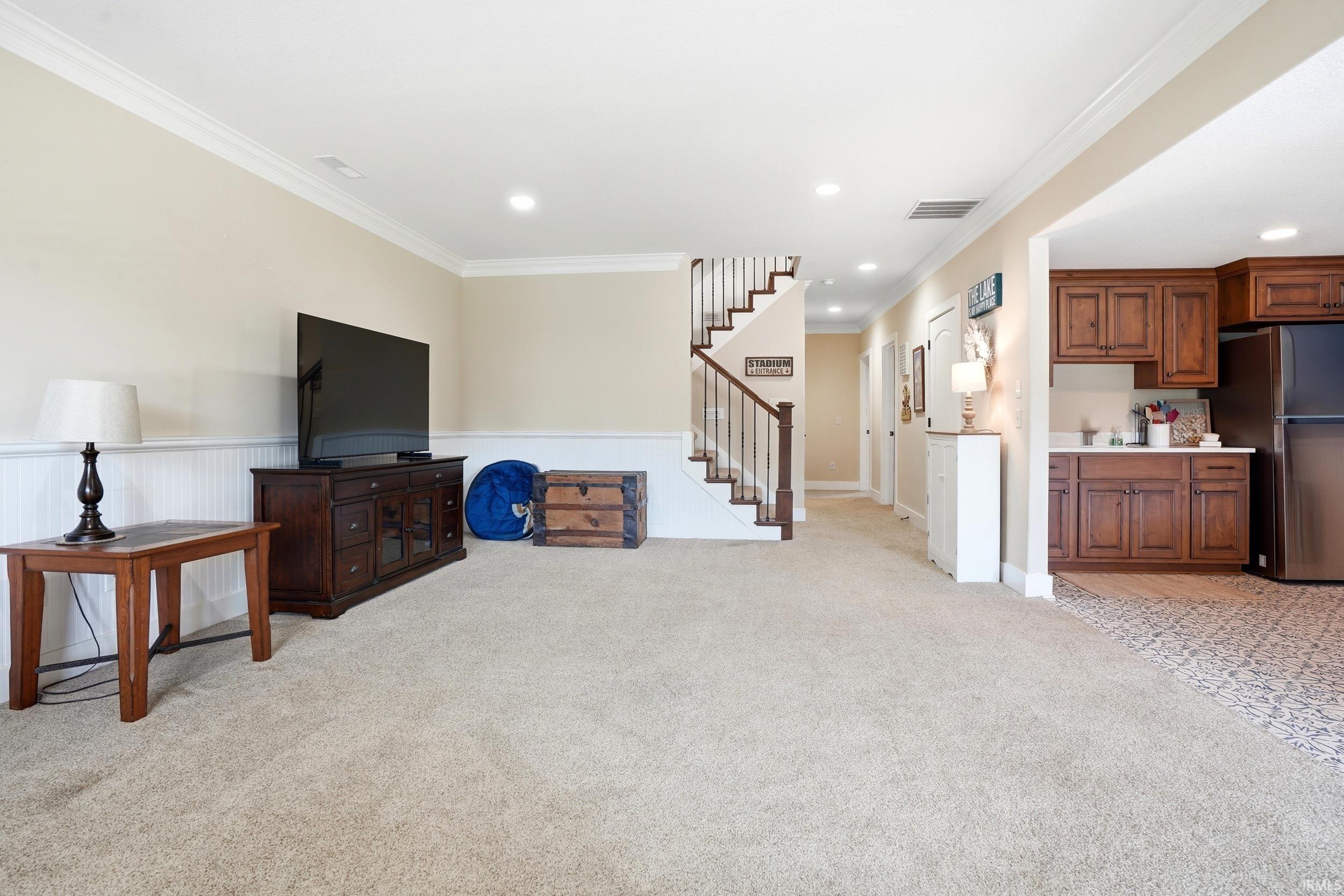 Spacious open-concept living area featuring gleaming carpet flooring, recessed lighting, and a wood-finish entertainment console