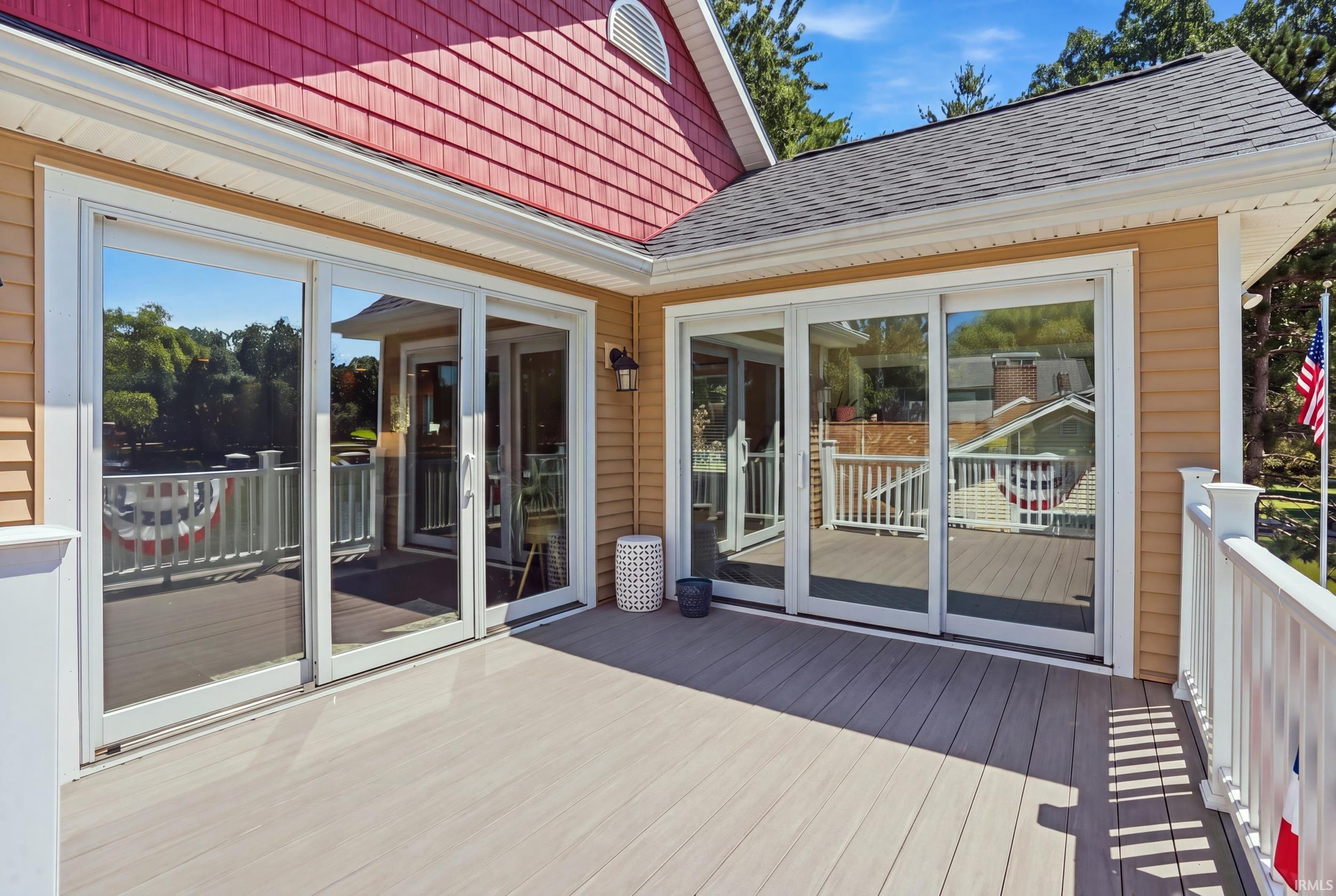 Expansive composite deck featuring multiple sets of French doors and sliding glass doors opening to outdoor living space