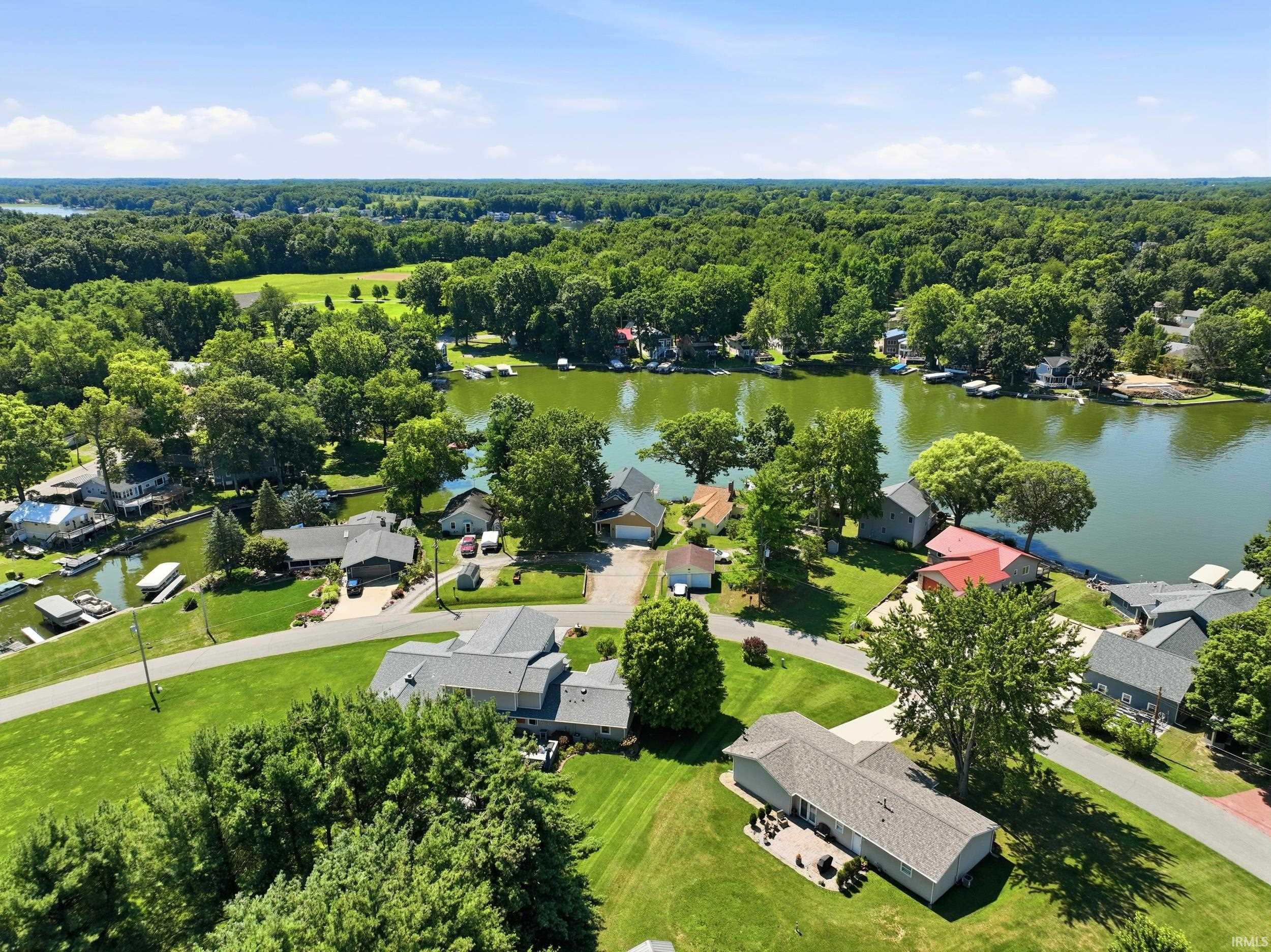 Waterfront residential community featuring multiple homes situated on expansive manicured lawns with mature tree coverage