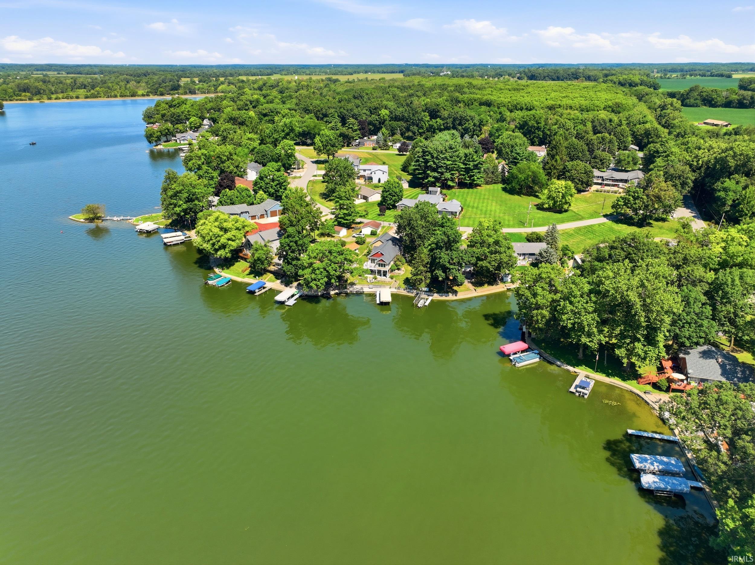 Waterfront estate nestled on expansive grounds featuring direct lake access with private dock, mature landscaping throughout the property, lush green lawn, tree-lined perimeter, and multiple residential structures