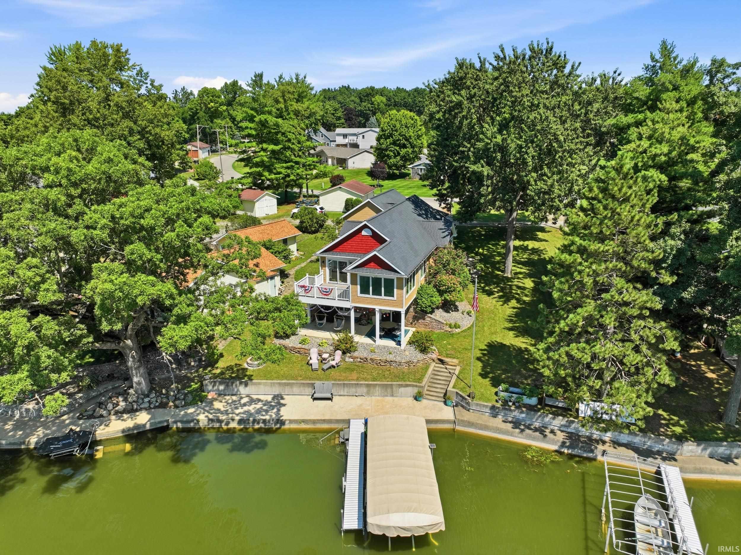 Waterfront residence featuring a contemporary design with black metal roof, yellow exterior siding, and multi-level deck access