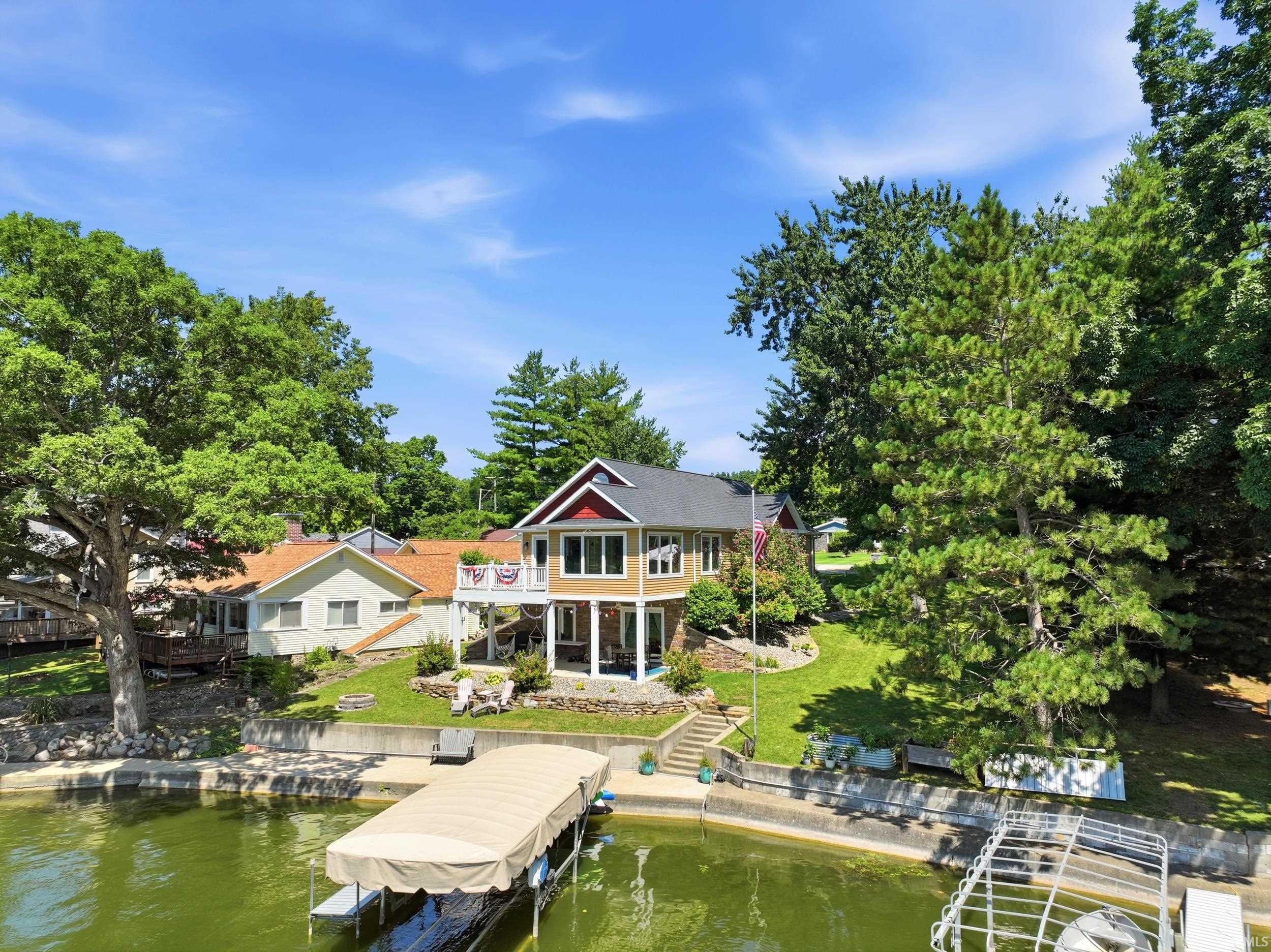 Waterfront residence featuring a two-story design with a covered balcony and an additional lower-level patio