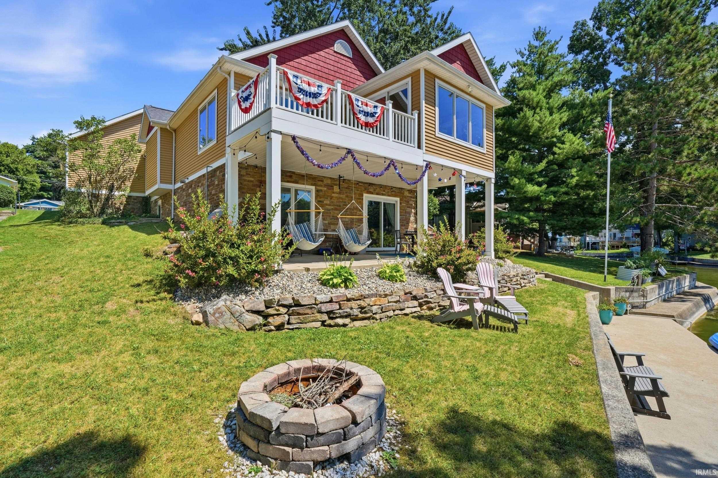 Charming two-story home with a tan exterior, red-roofed peaks, and white trim details