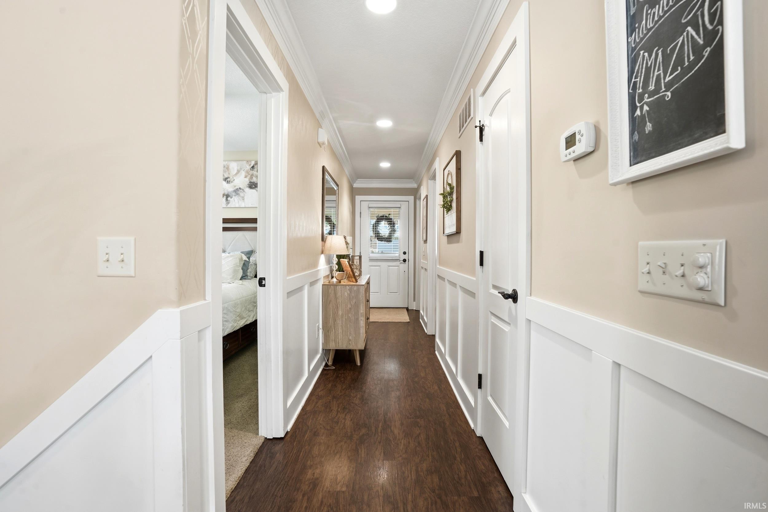 Hallway featuring wood-finish flooring, white wainscoting, and recessed lighting