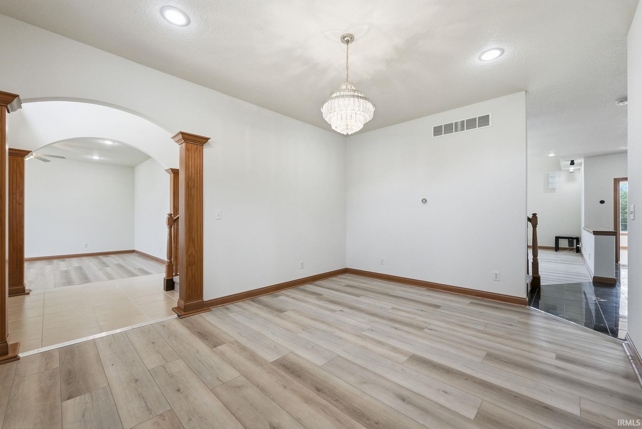 Open concept living space featuring light wood-finish flooring, a tiered crystal chandelier, recessed lighting, and white baseboards