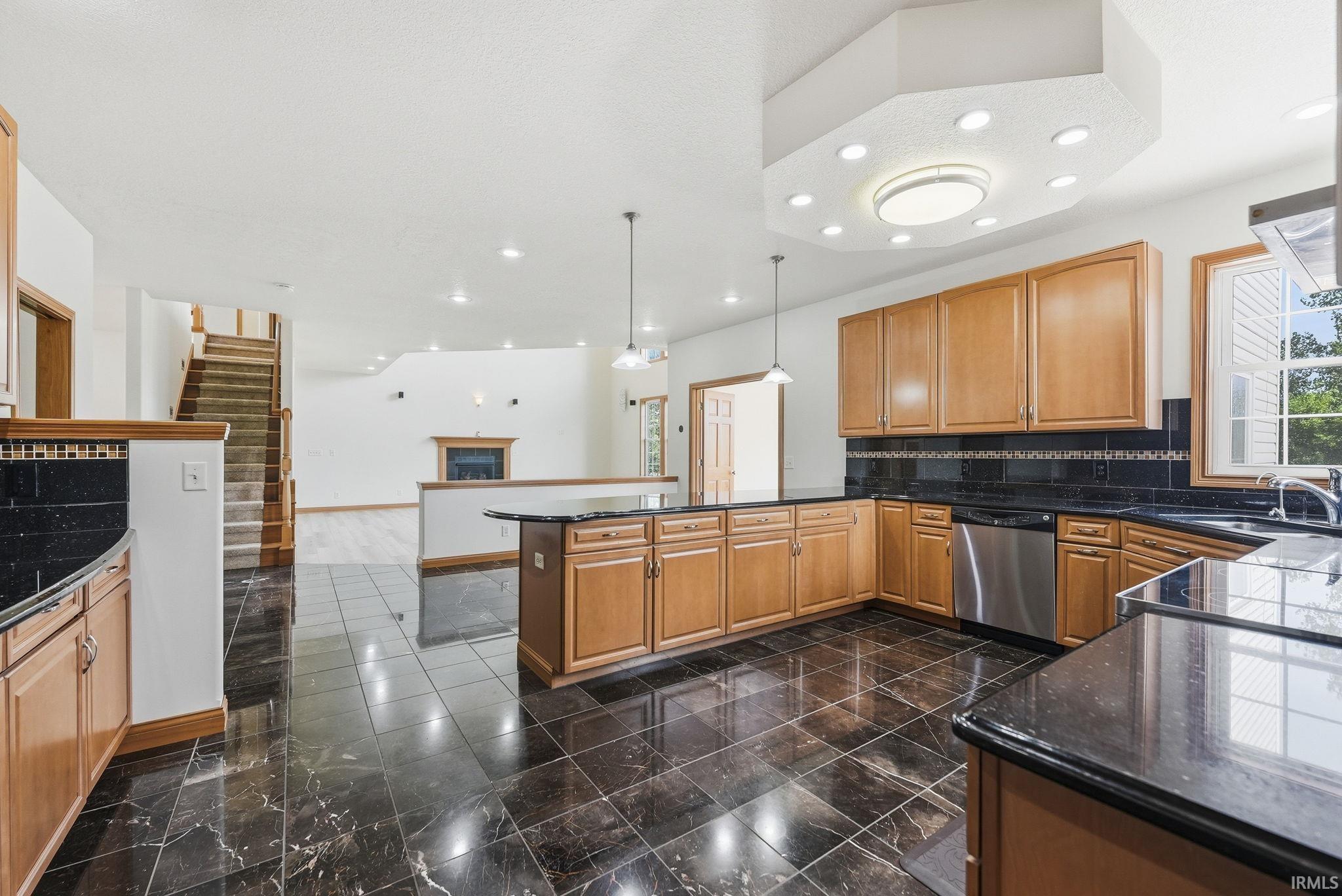 Kitchen featuring black tile flooring, light wood cabinetry, dark countertops, and stainless steel appliances