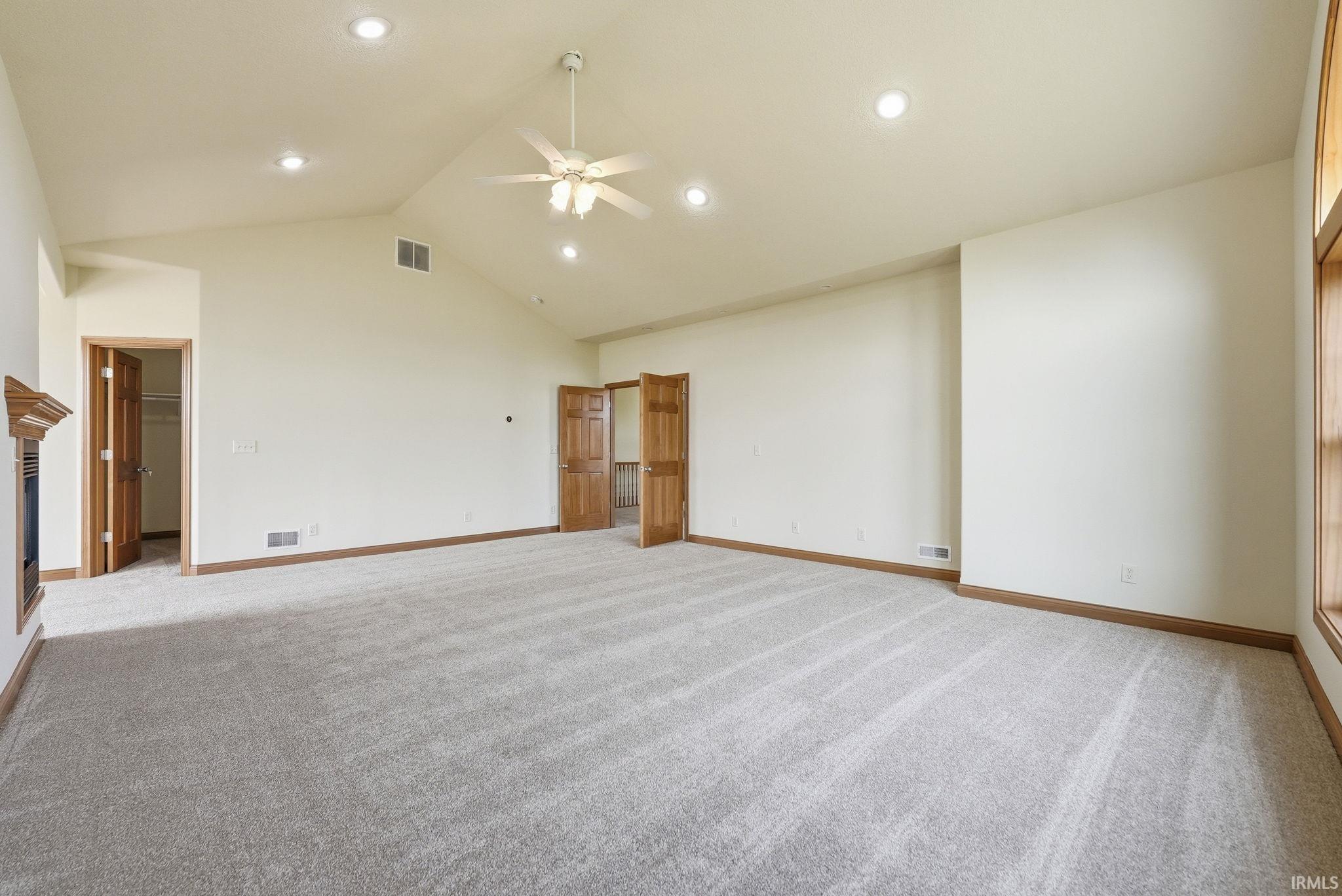 Spacious interior room featuring vaulted ceilings, recessed lighting, and a ceiling fan