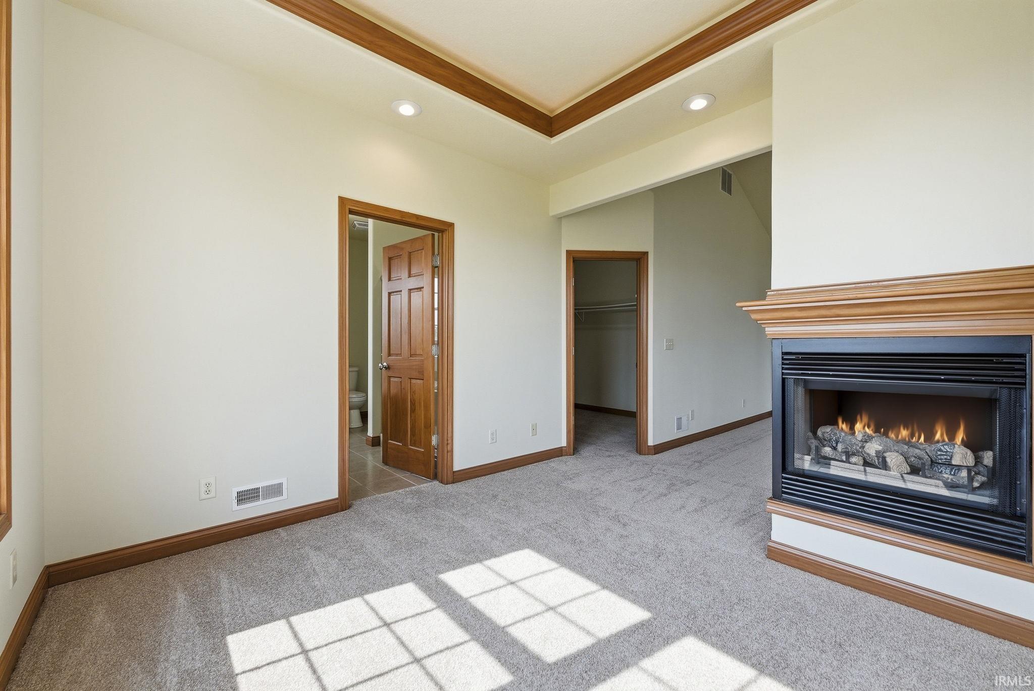 Interior space featuring a built-in fireplace with a traditional wood mantle, recessed lighting, and a tray ceiling with wood trim