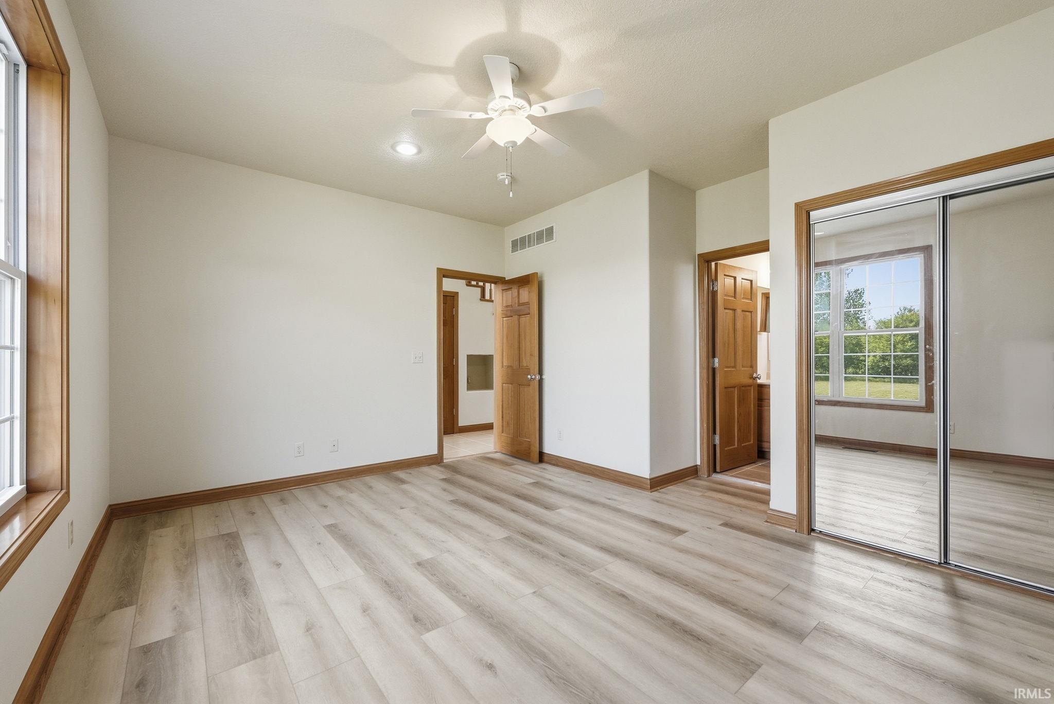 Spacious room featuring wood-finish flooring, white walls, and wood trim