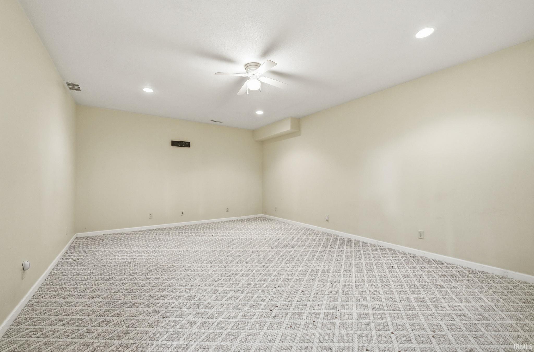 Spacious room featuring patterned carpeting and neutral wall tones