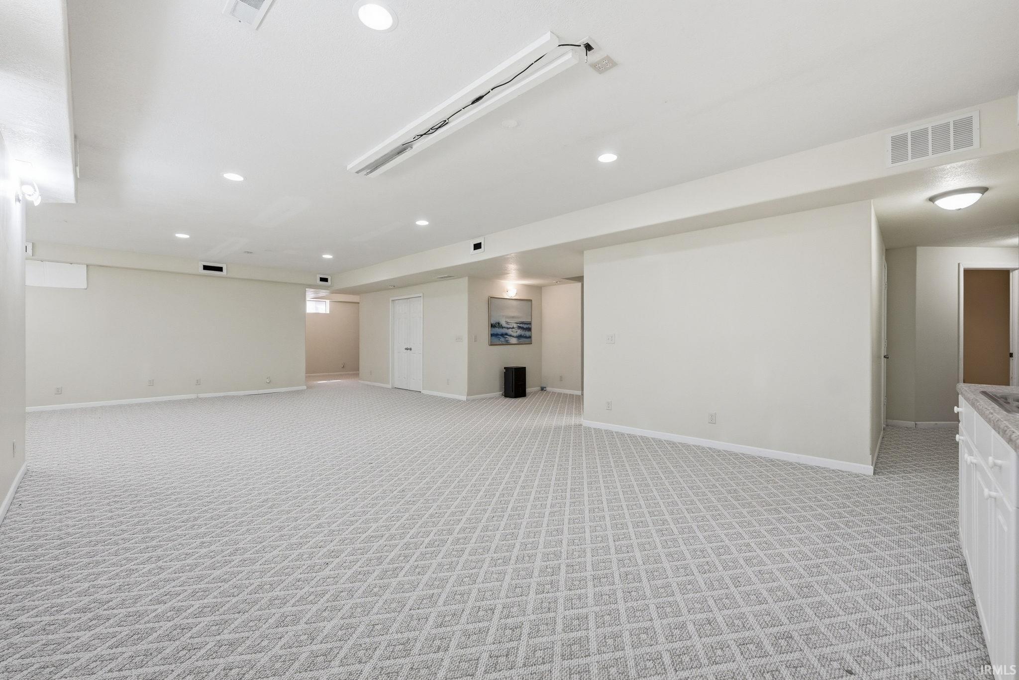 Spacious room featuring patterned carpet flooring, recessed lighting, and a neutral color palette