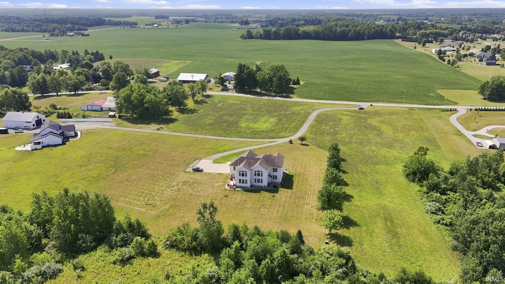 Aerial perspective showcasing a multi-level residence with a white exterior, set on a graded lot