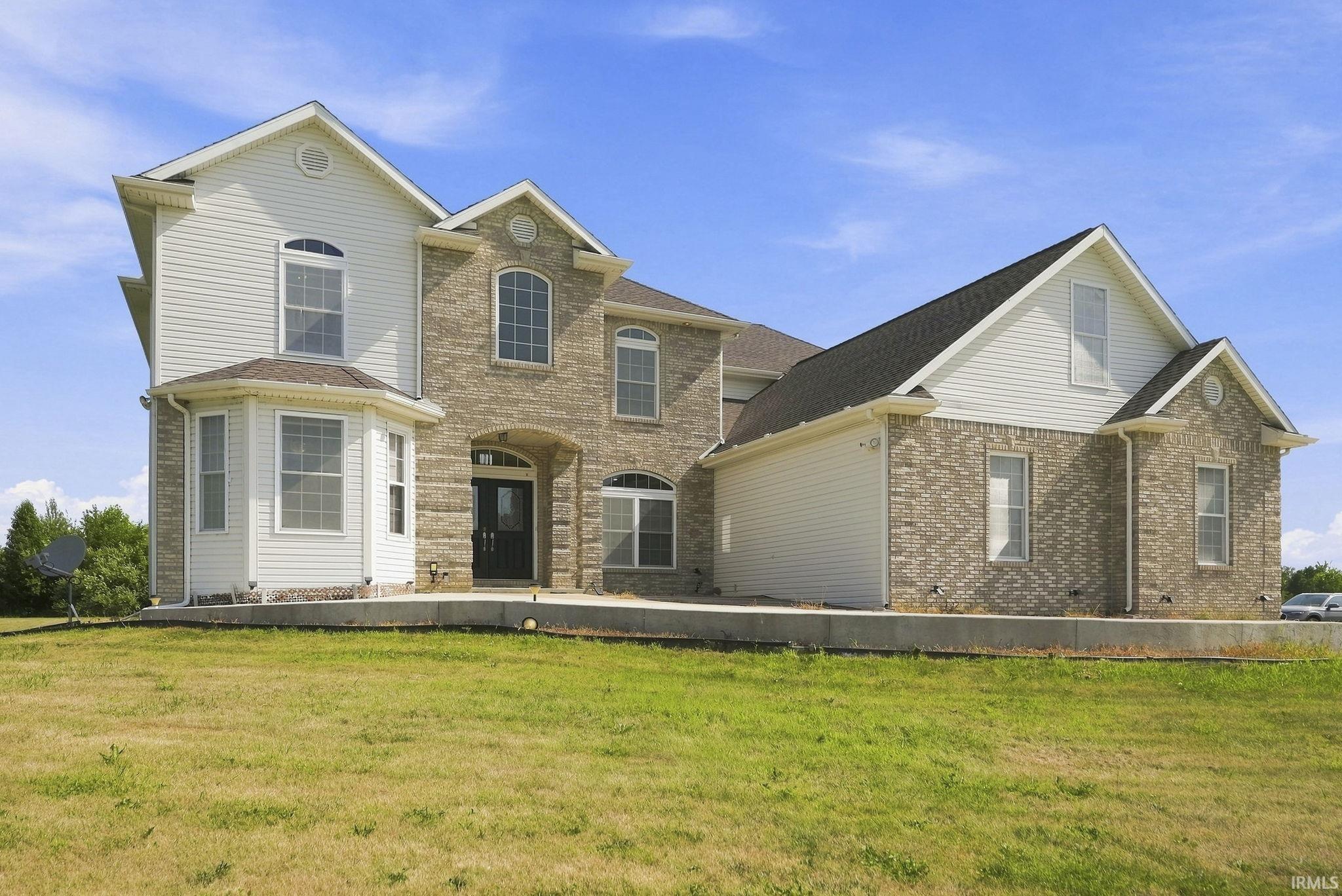 Contemporary multi-story residence featuring a brick and siding exterior, arched entry, and prominent bay window