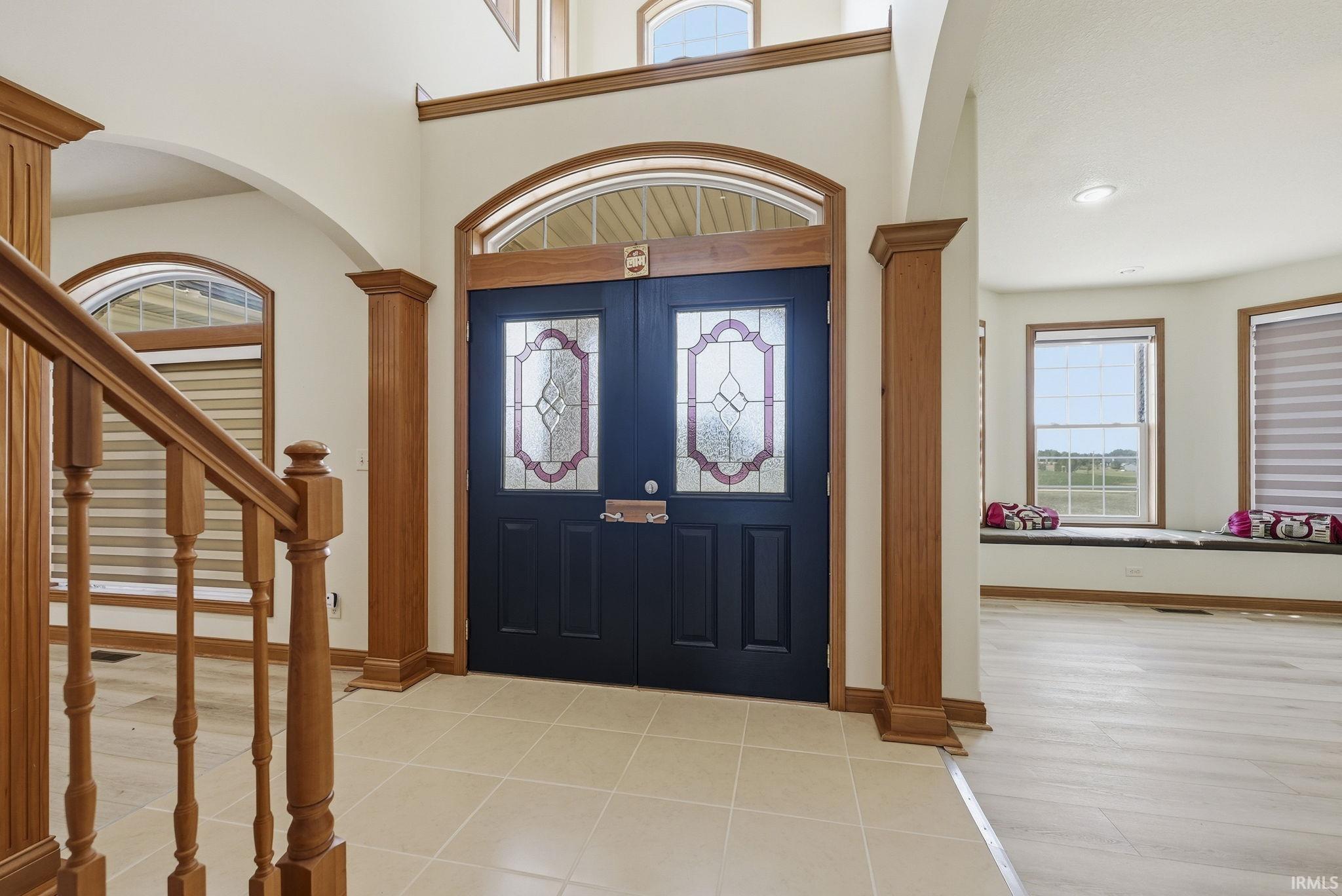 Double entry doors with decorative leaded glass inserts and an arched transom window
