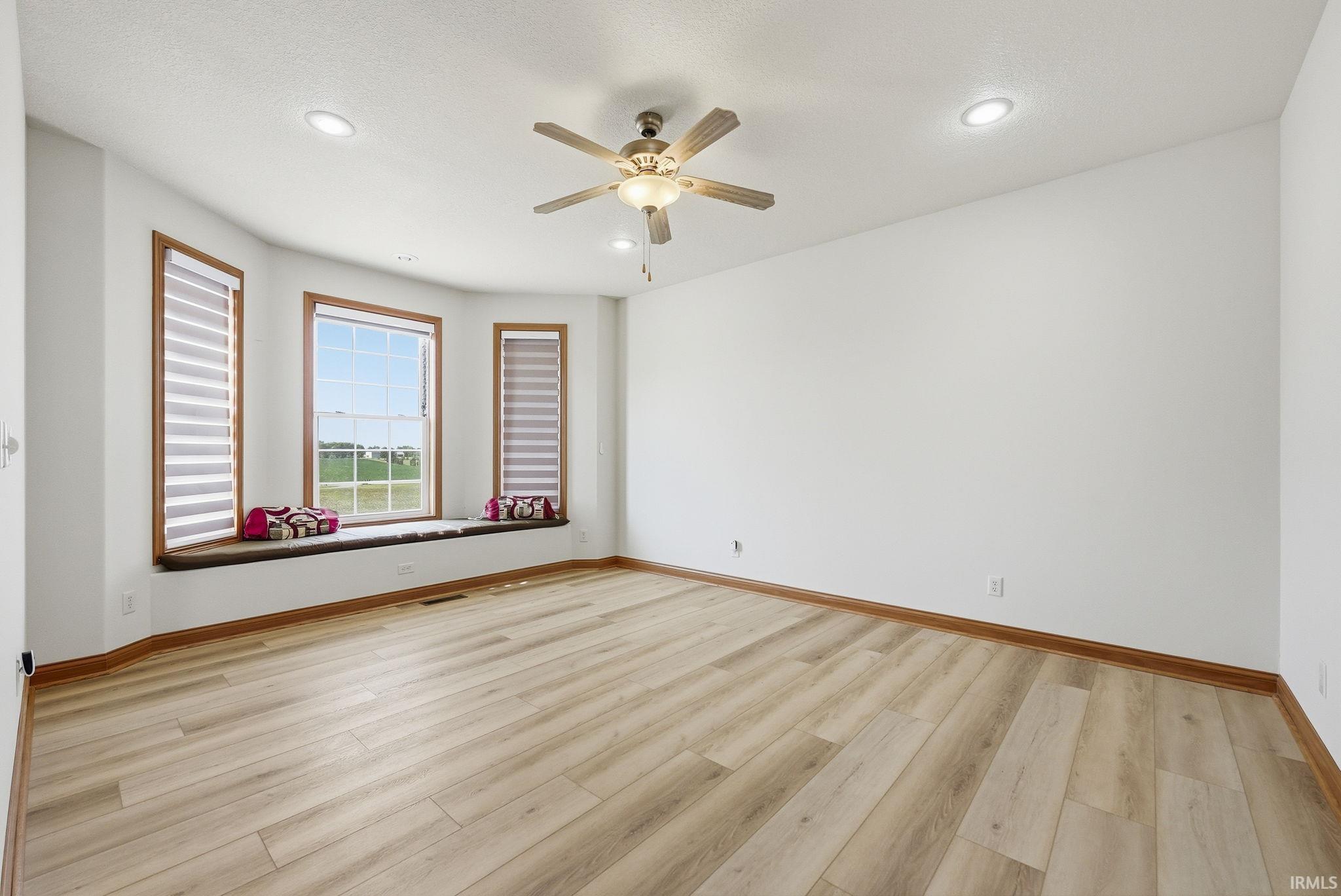 Spacious room featuring light wood-finish flooring and a bay window with a built-in window seat