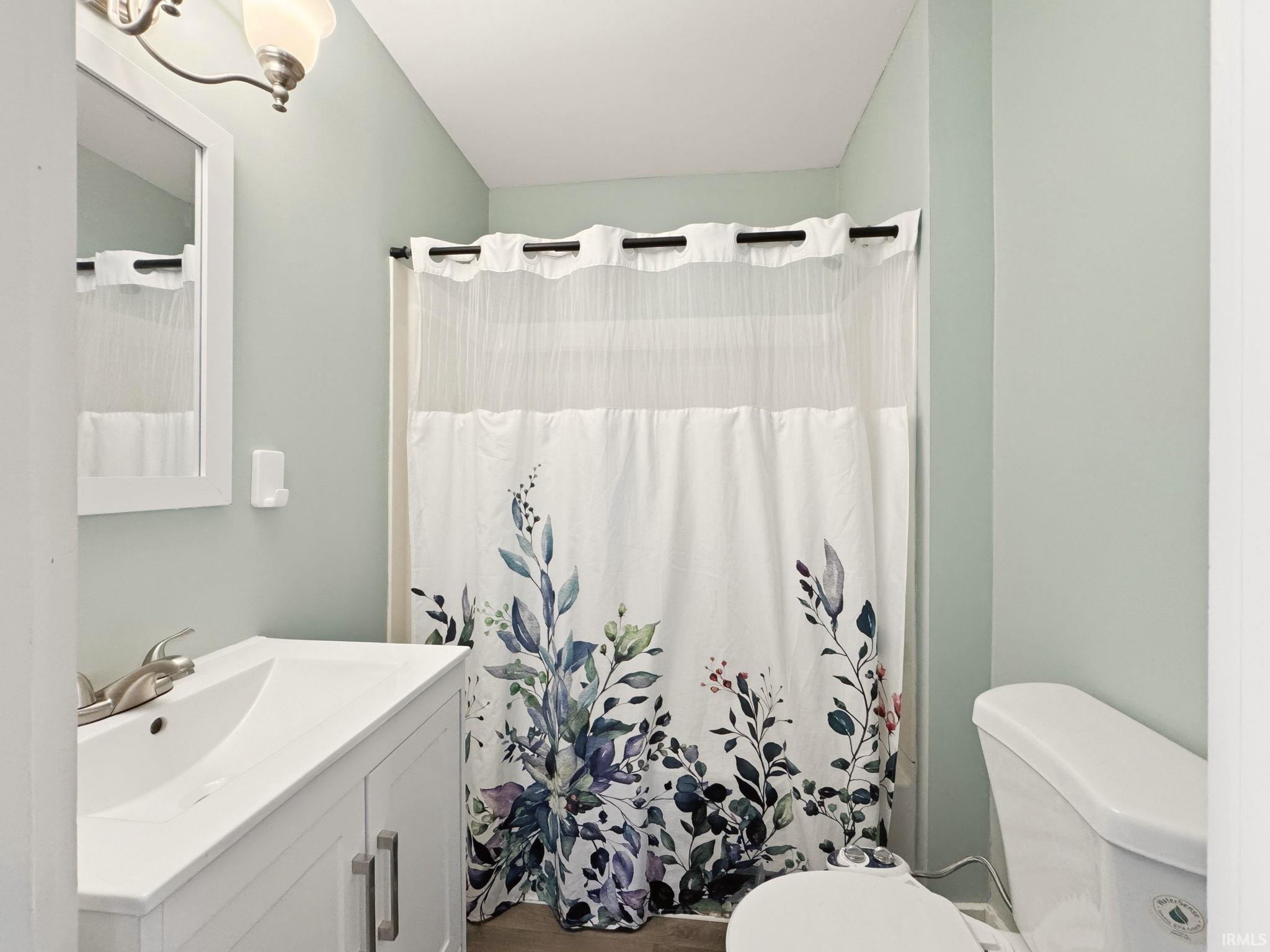 Bathroom featuring a white vanity with integrated sink, brushed nickel faucet, matching mirror, and a toilet