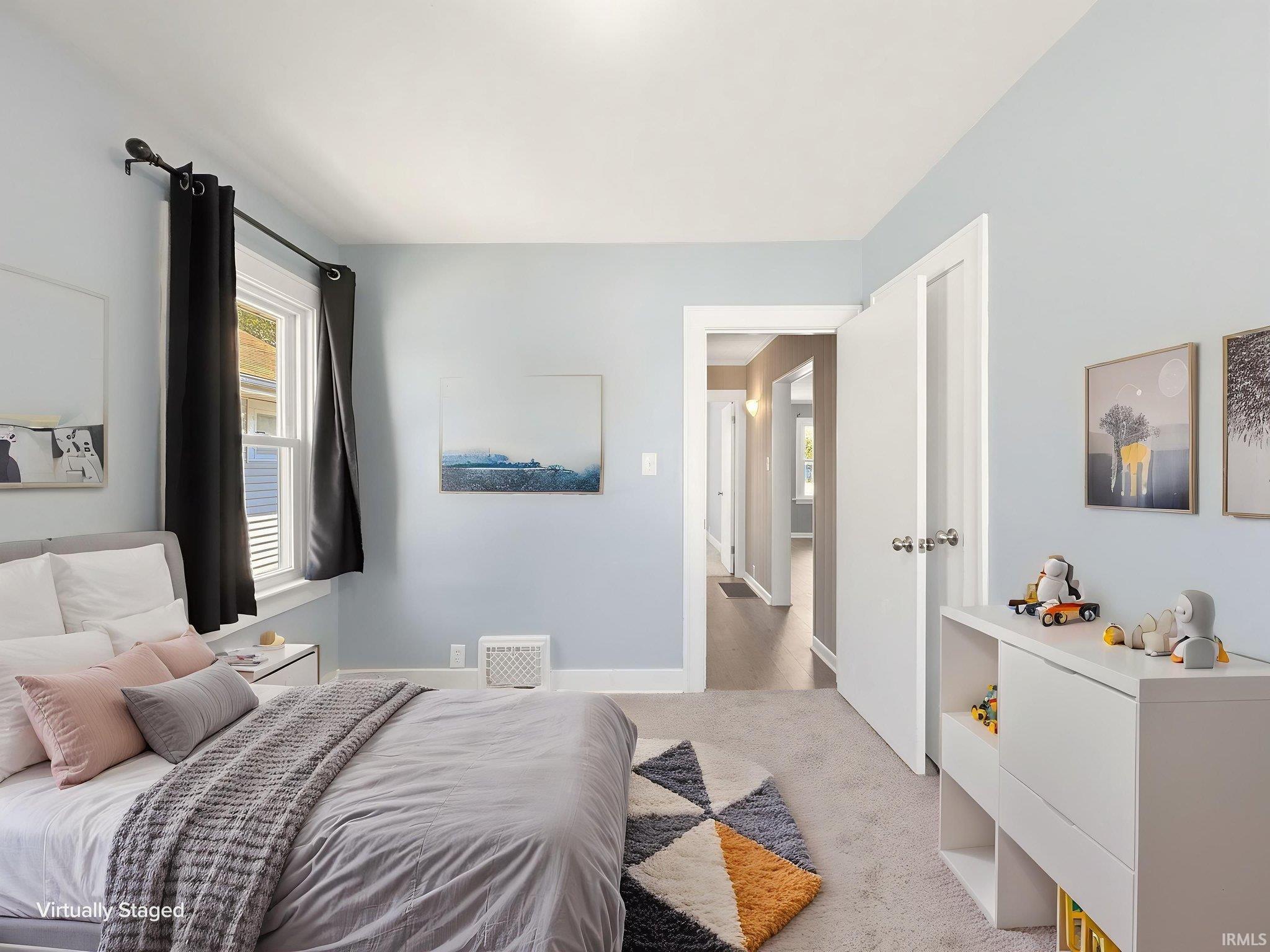 Light blue walls with white trim, carpeting, and a window with black drapes