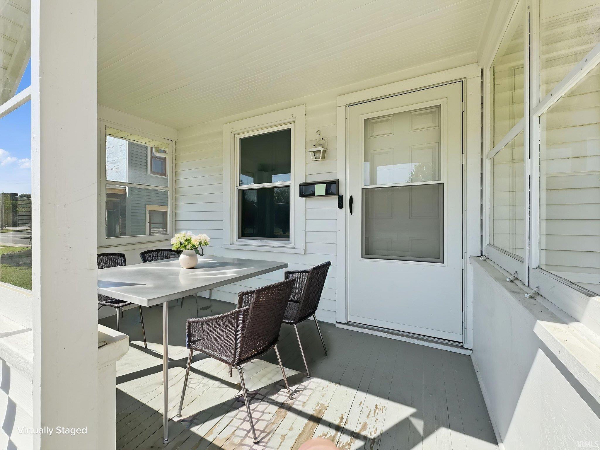 Enclosed front porch featuring white siding, a white entry door, and multiple windows