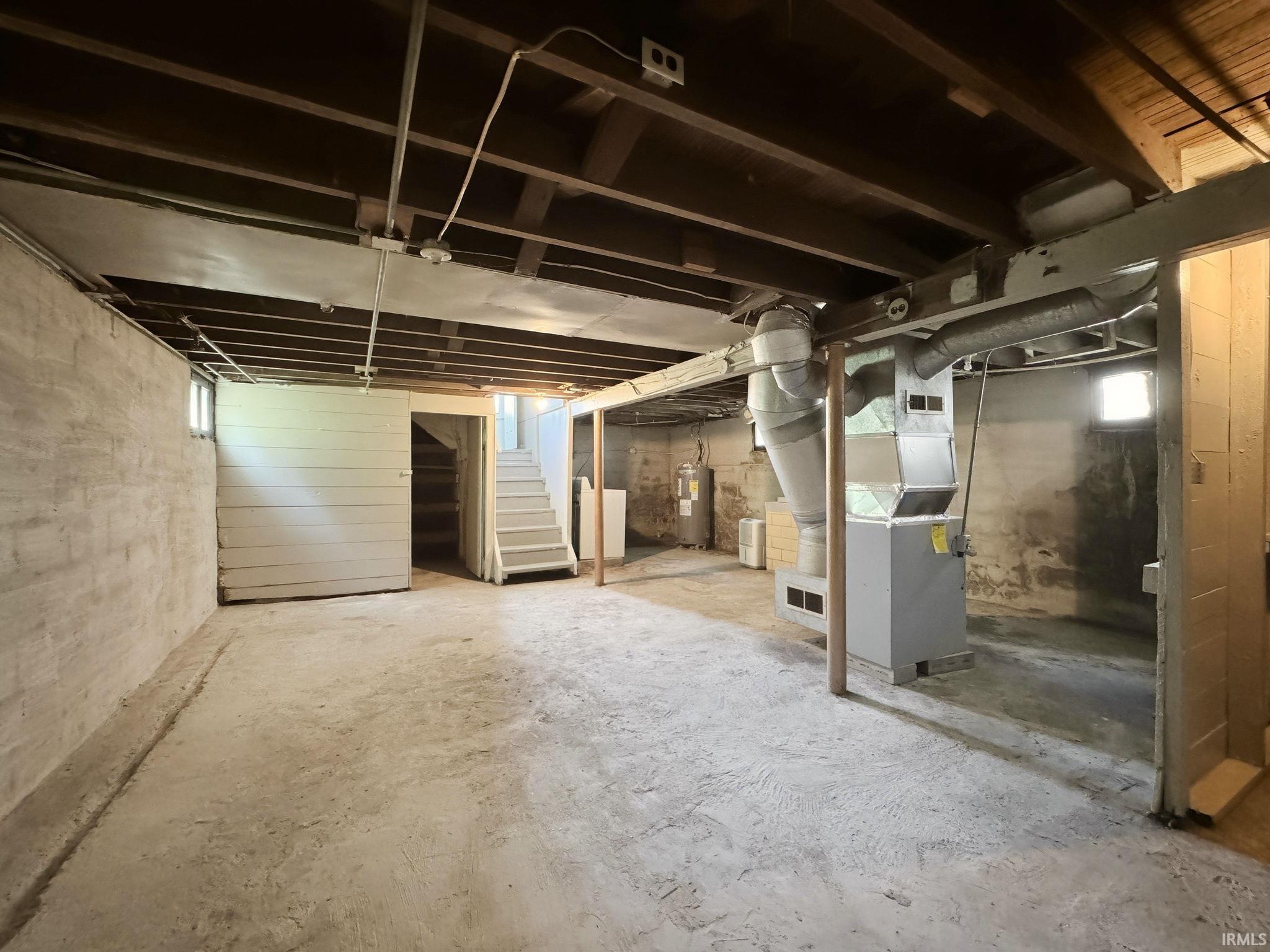 Unfinished basement featuring exposed wood joists, concrete flooring, and visible ductwork