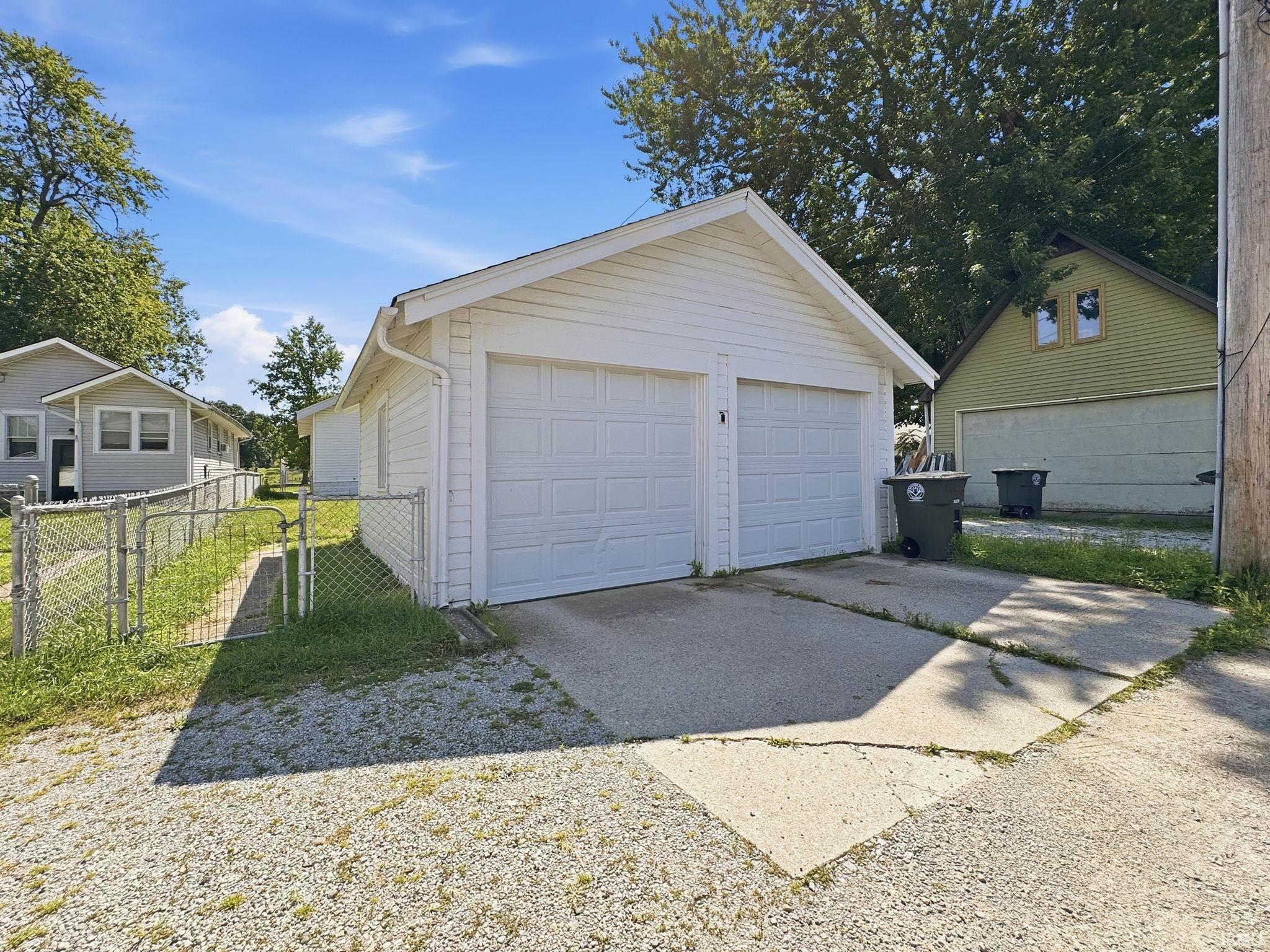 Detached two-car garage with white vinyl siding and dual overhead doors