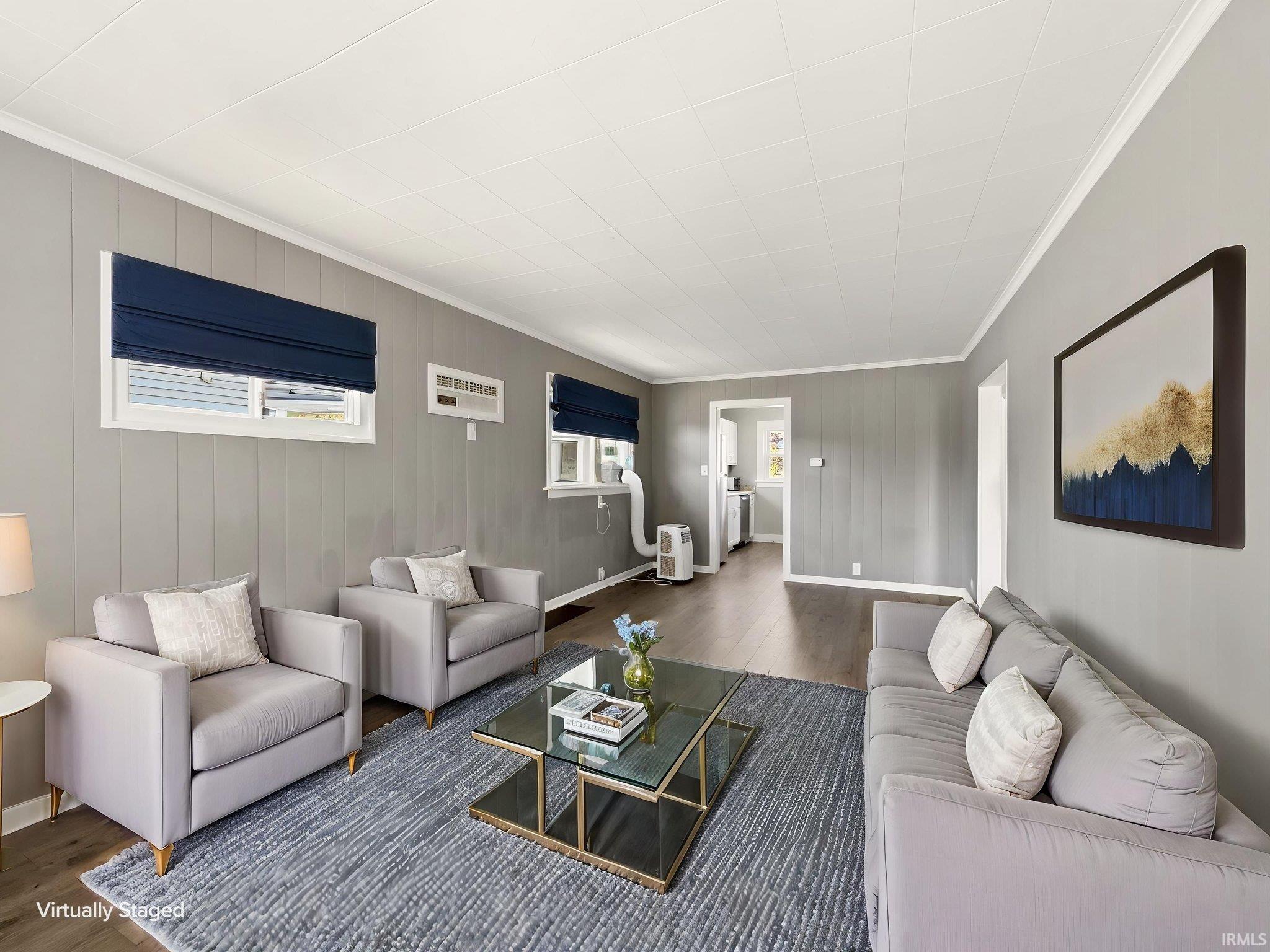 Spacious living area featuring wood-finish flooring, vertical paneling, white trim, and a white ceiling