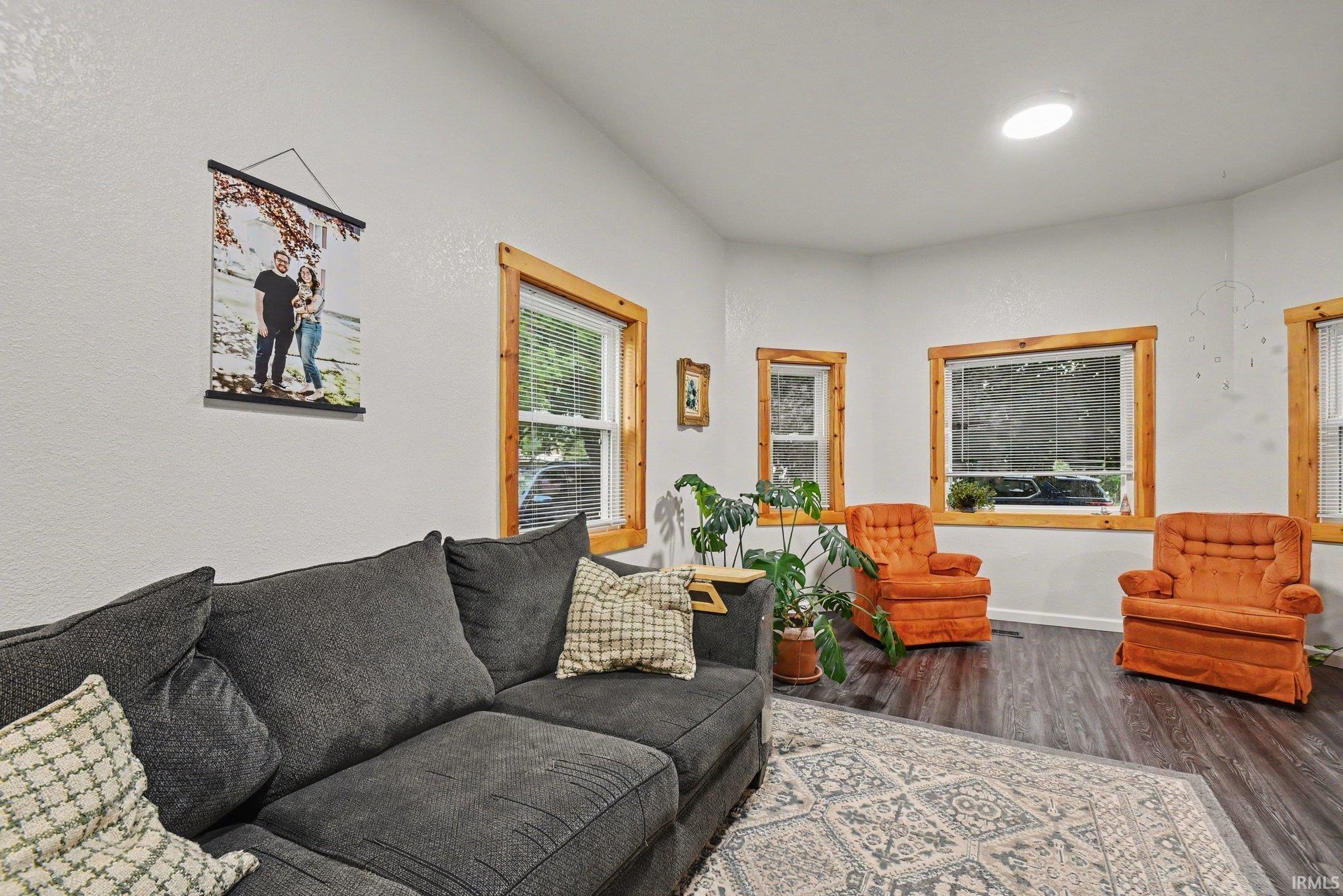 Living area featuring wood-finish flooring and multiple windows with natural wood trim