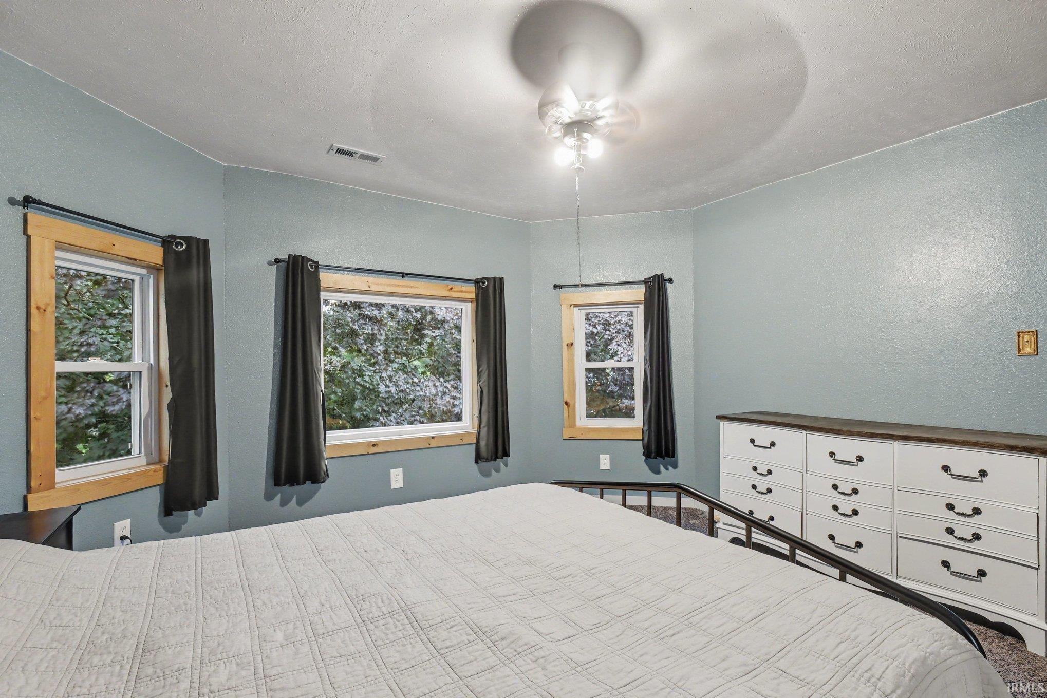Interior space featuring multiple windows with natural wood trim, a ceiling fan with integrated lighting, and light blue wall finishes