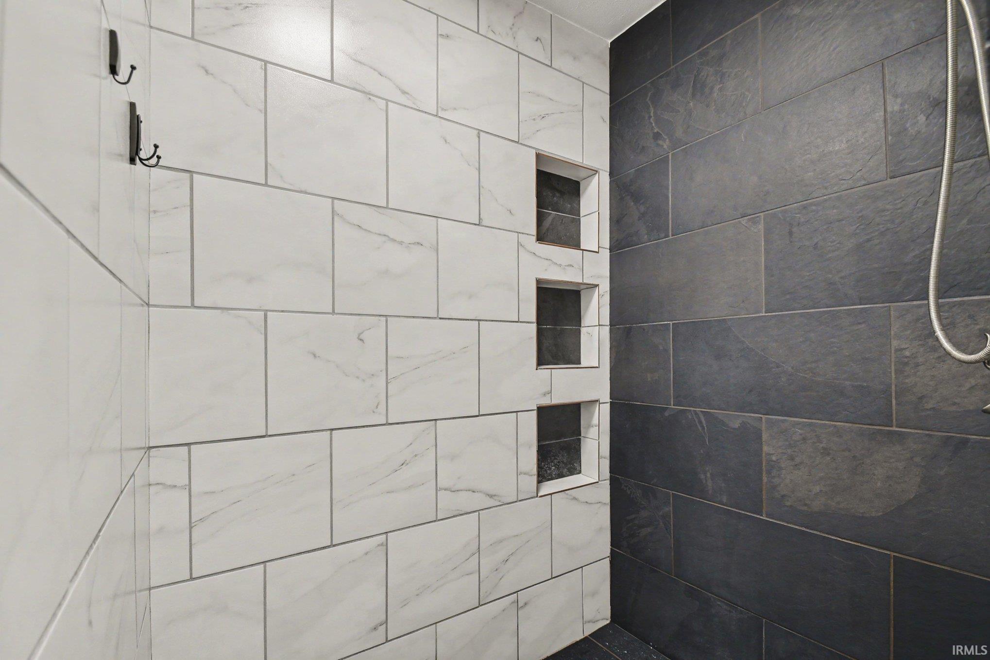 Shower enclosure featuring white marble-look subway tile and dark slate-look rectangular tile
