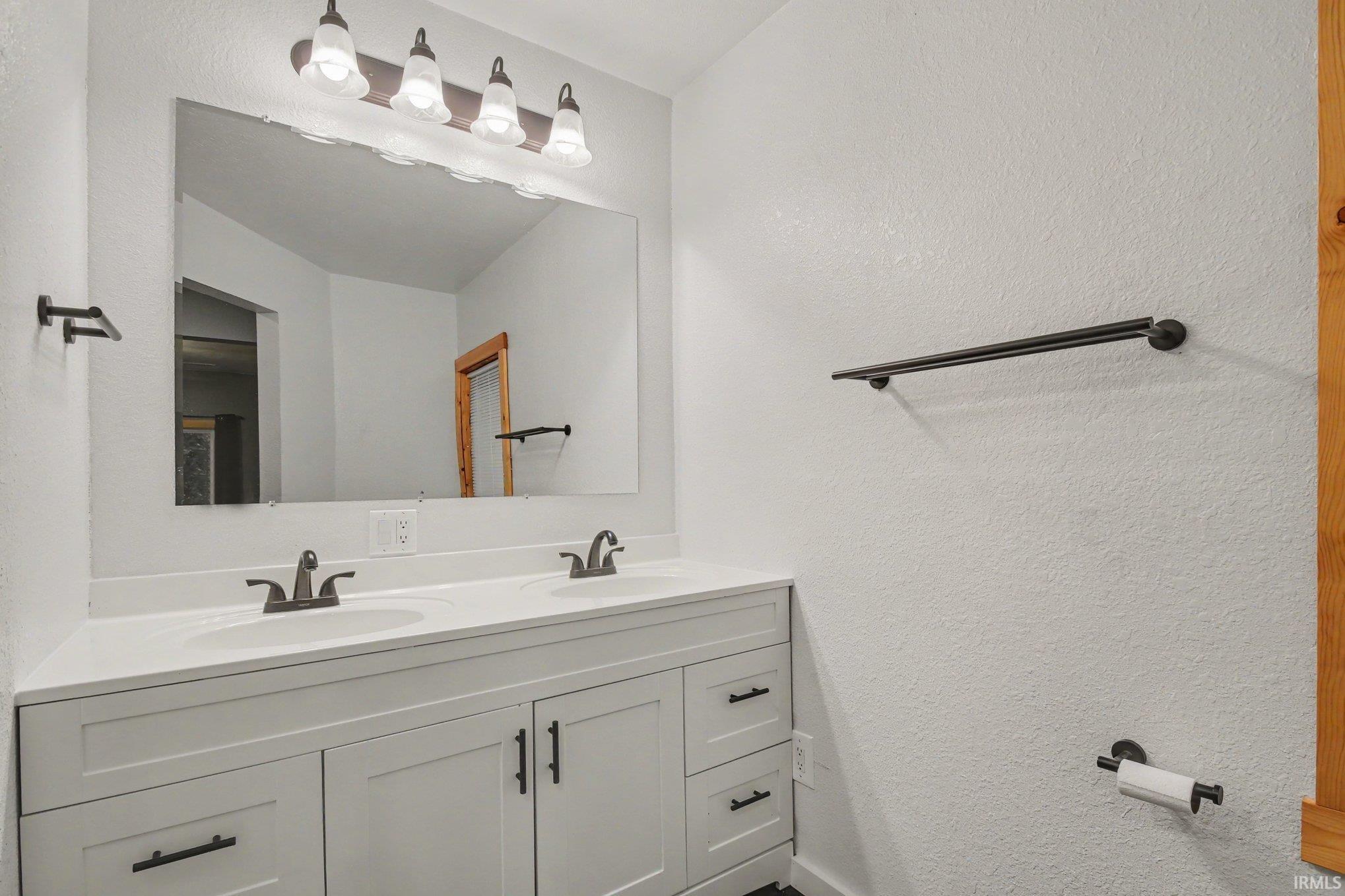 Dual sink vanity with white cabinetry, integrated sinks, and dark bronze-finish fixtures
