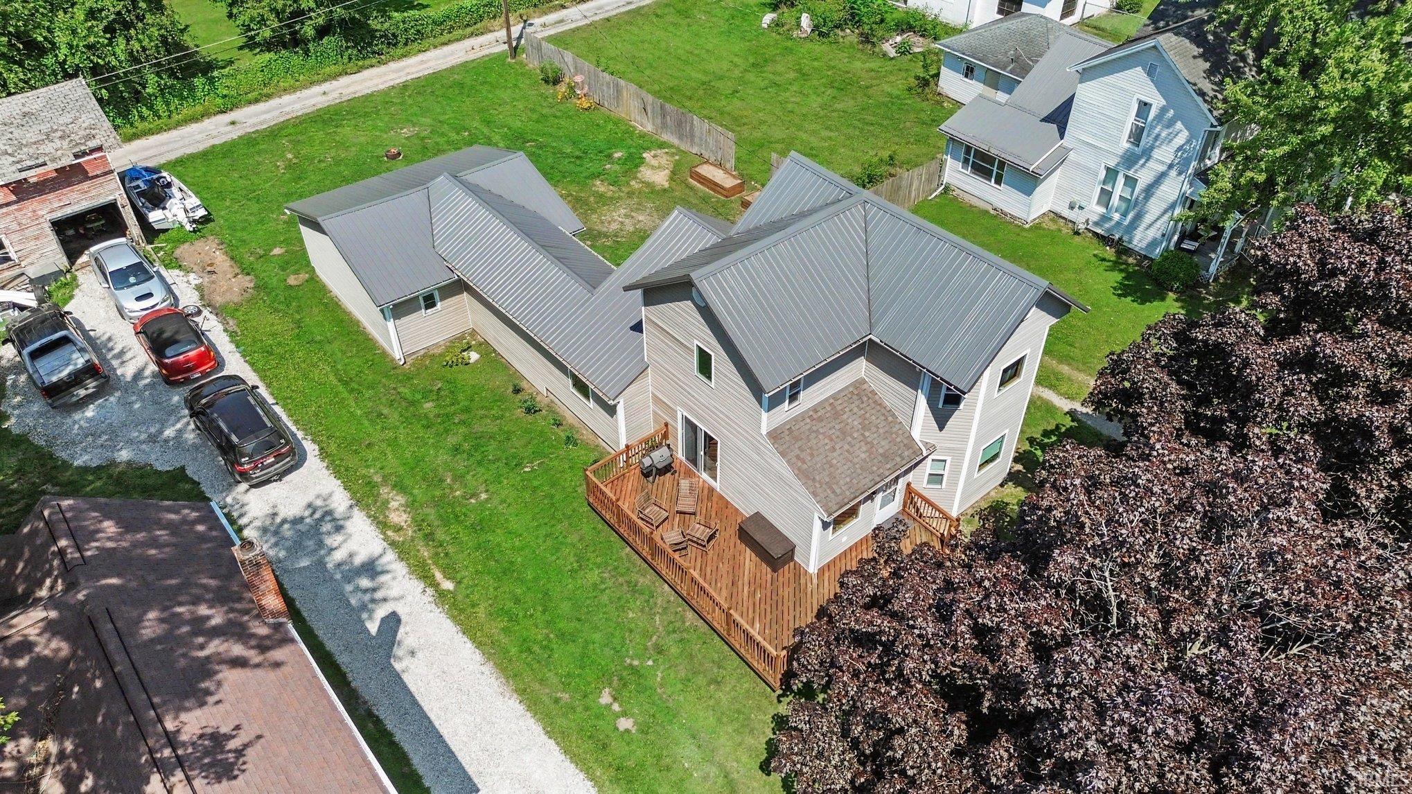 Contemporary residence featuring a multi-level composite deck, light gray siding, and a standing seam metal roof